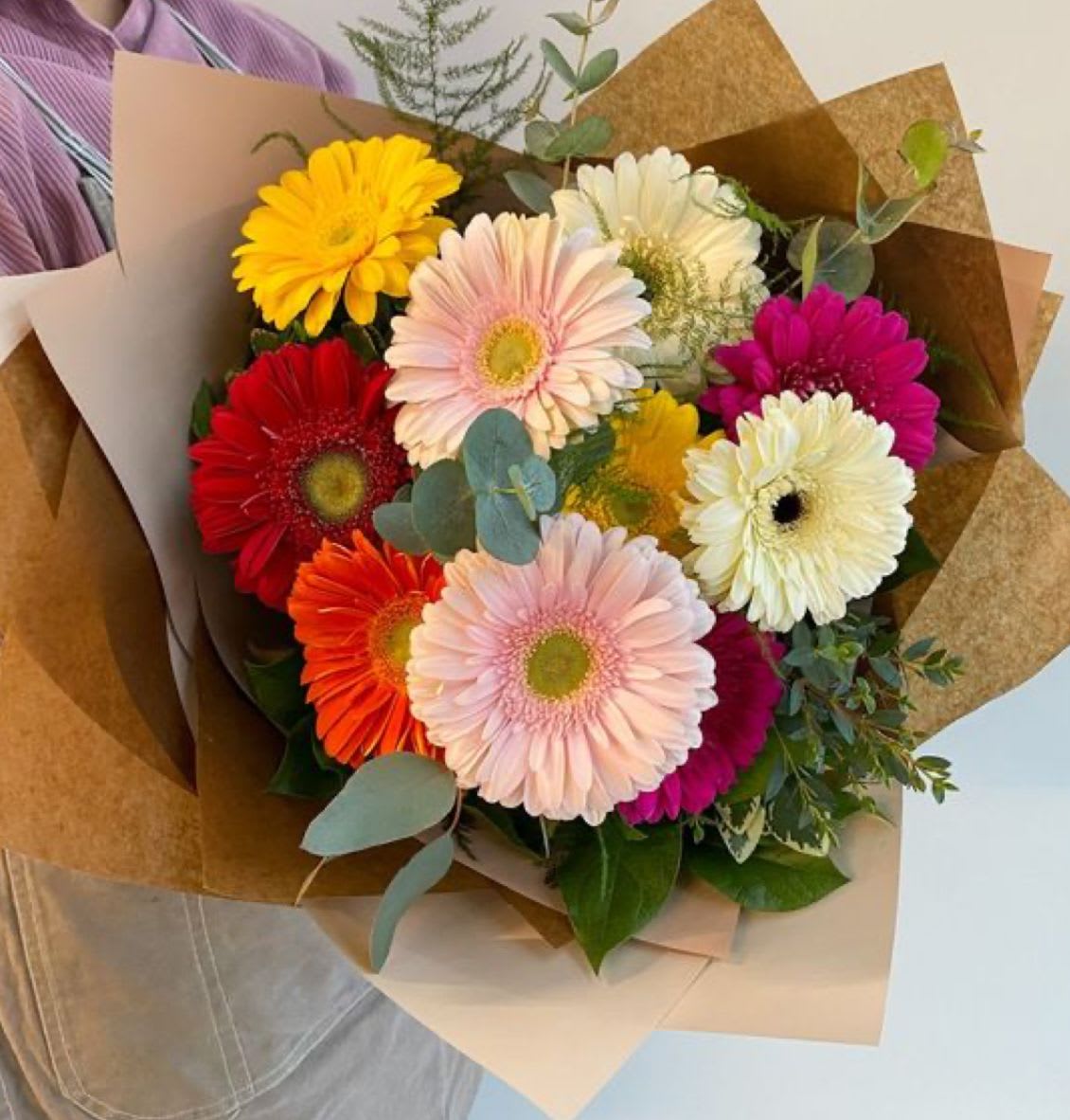 Bouquet of multicolored gerbera daisies wrapped in brown paper