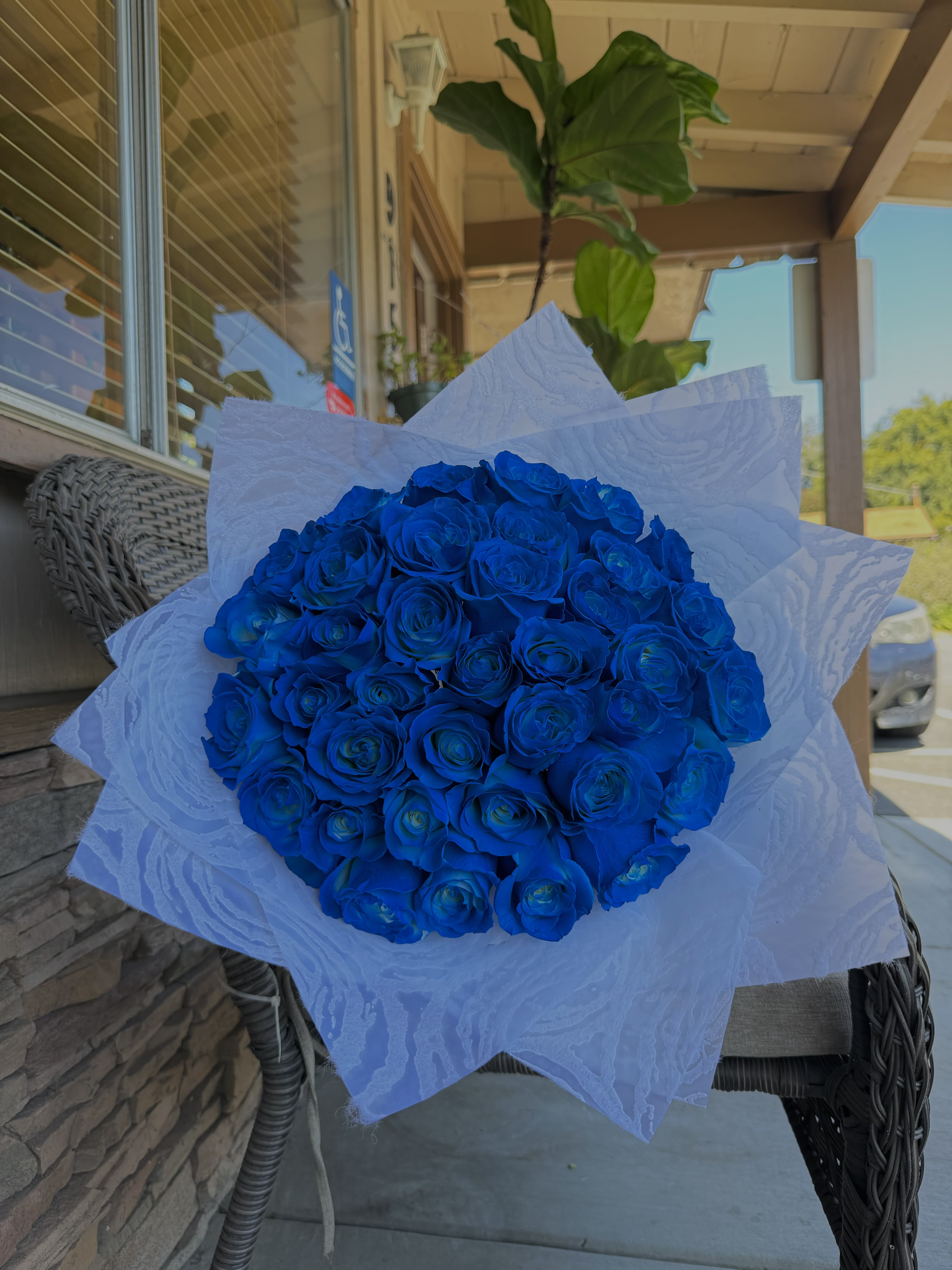 Bouquet of vivid blue roses wrapped in white paper
