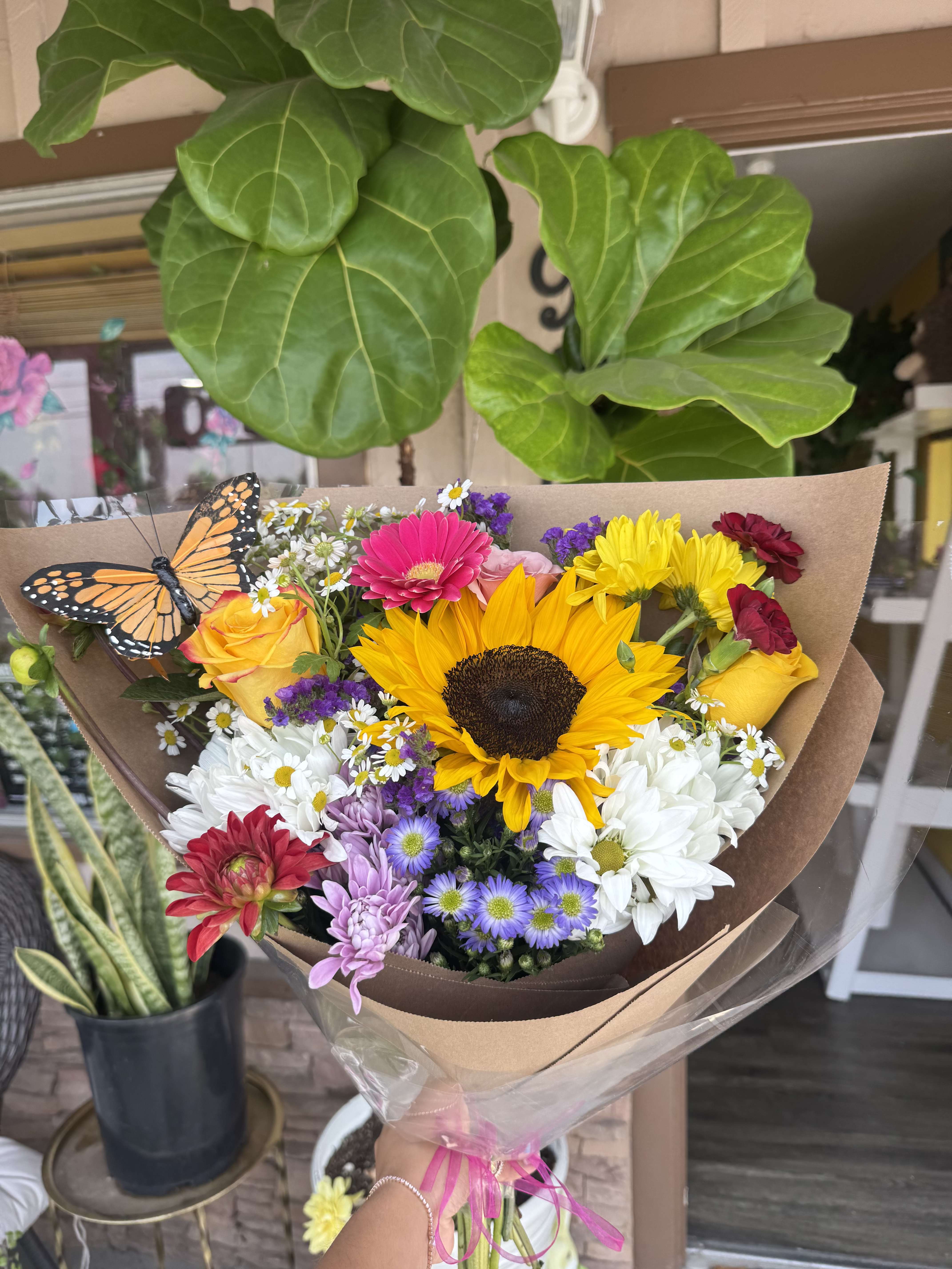 Colorful mixed bouquet with a sunflower and roses, wrapped in brown paper