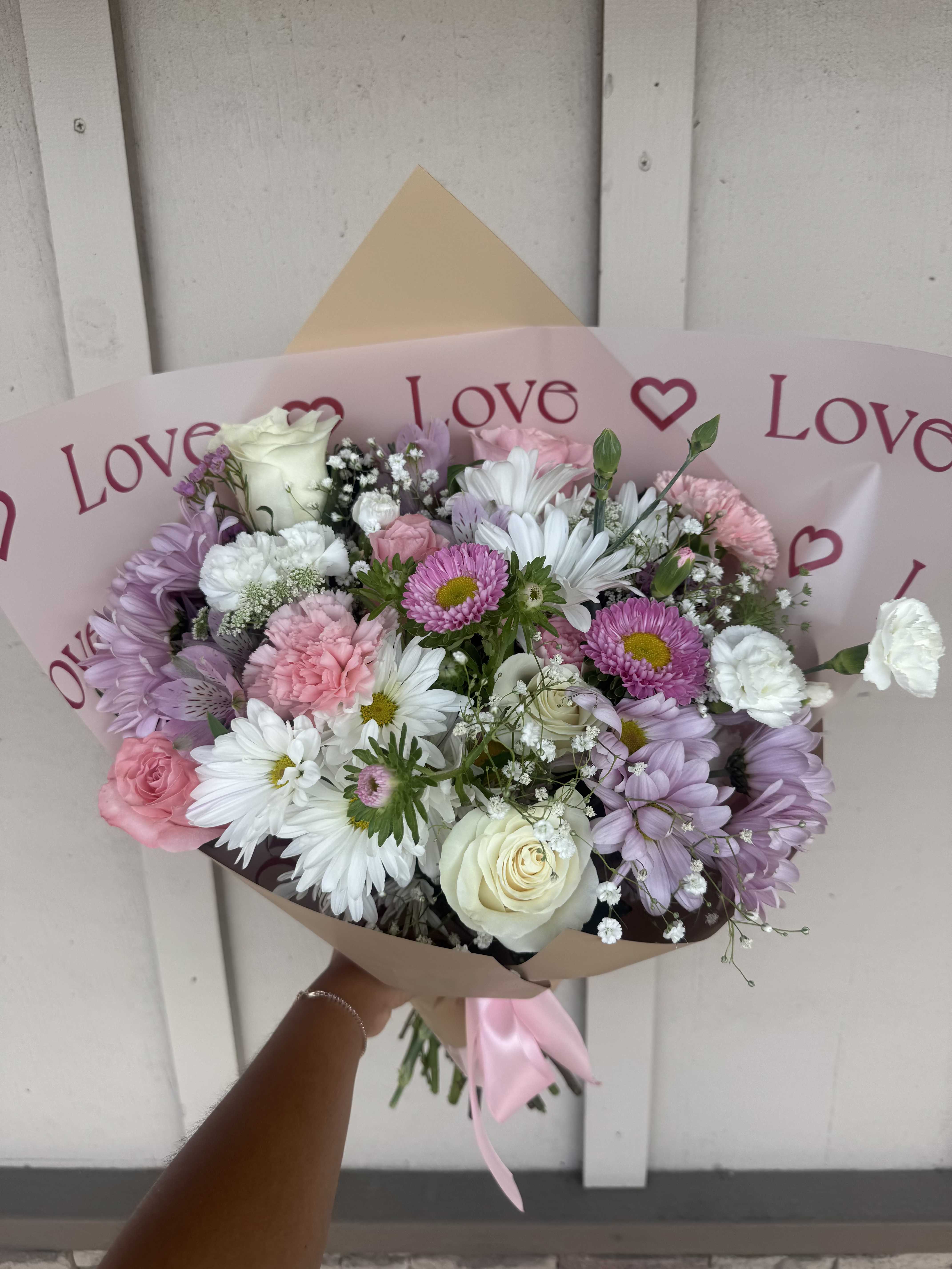 Pink and white mixed bouquet wrapped in paper with a satin ribbon