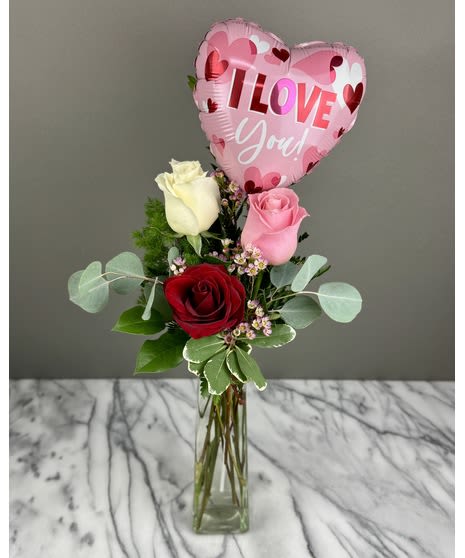 Roses in a glass vase with a pink heart balloon