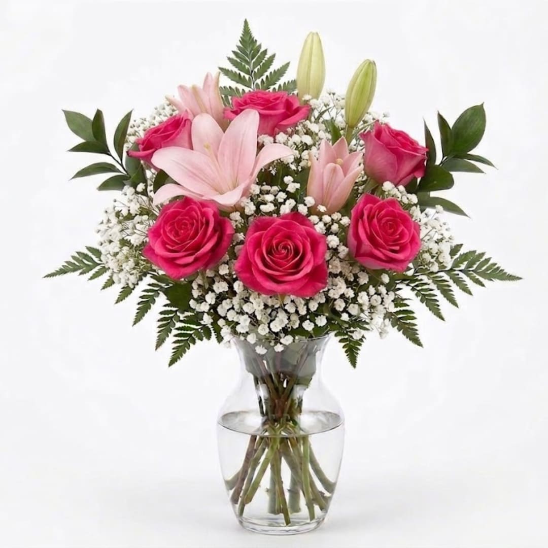 Pink roses and lilies arranged in a clear glass vase