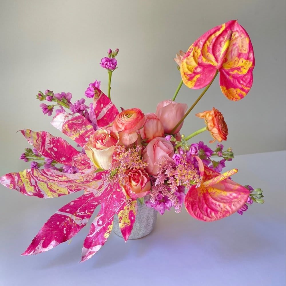 Pink and orange floral arrangement in a small gray vase