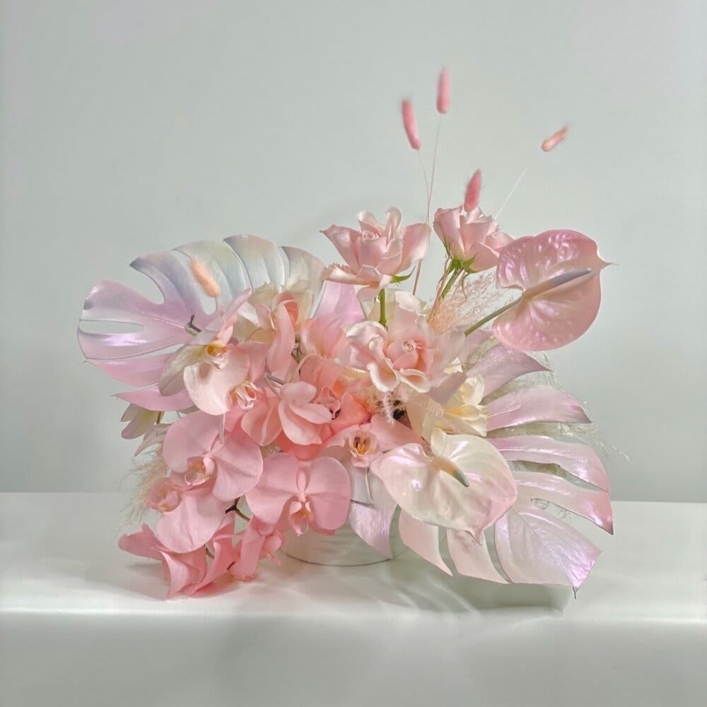 Pink and white orchid arrangement in a low container