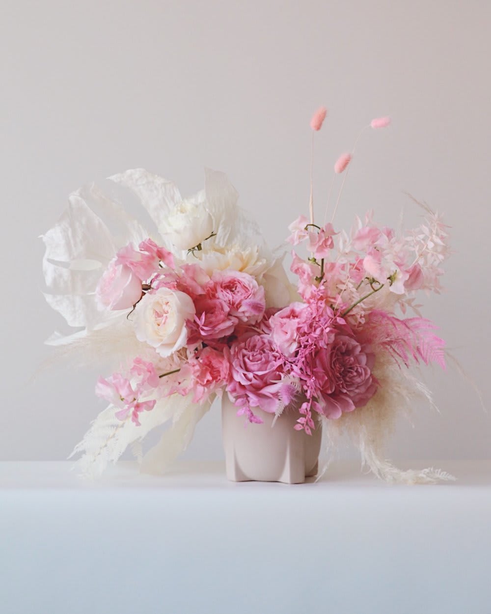 Pink and white floral arrangement in a pale vase