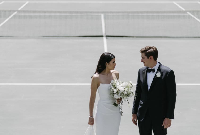 Bride holding a white bouquet beside a groom in a tuxedo