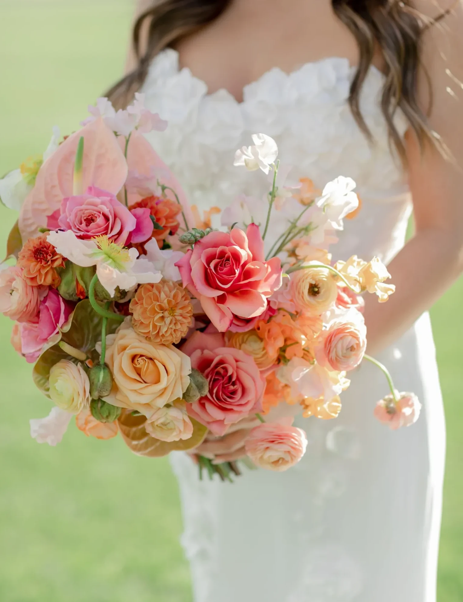 Bride holding a pastel bouquet of roses, ranunculus, and orchids
