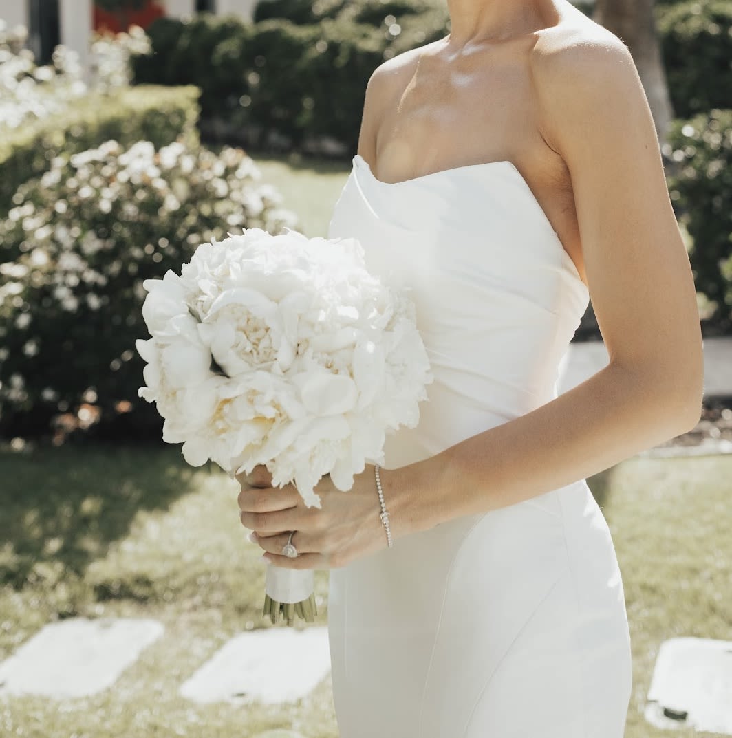 Bride holding a white bouquet in a strapless dress outdoors