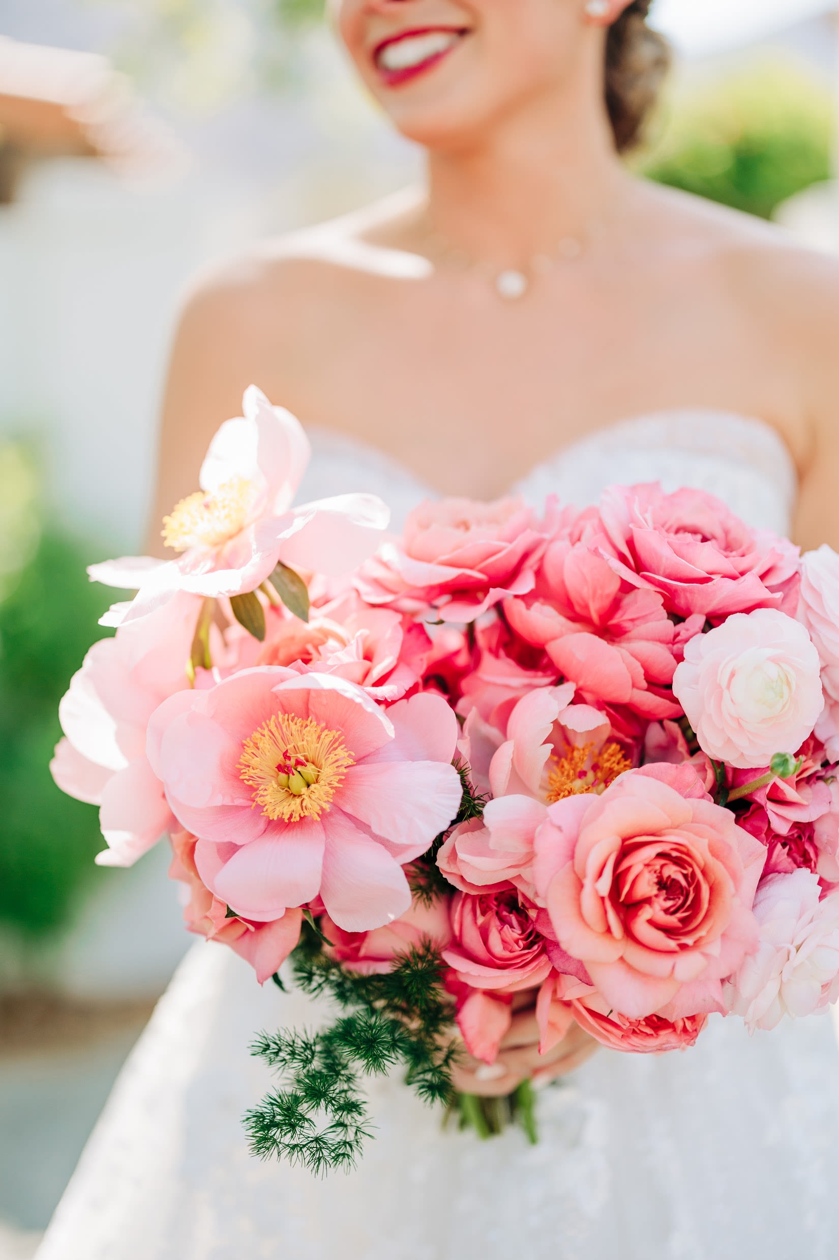 Bride holding a pink bouquet with roses and peony-like blooms