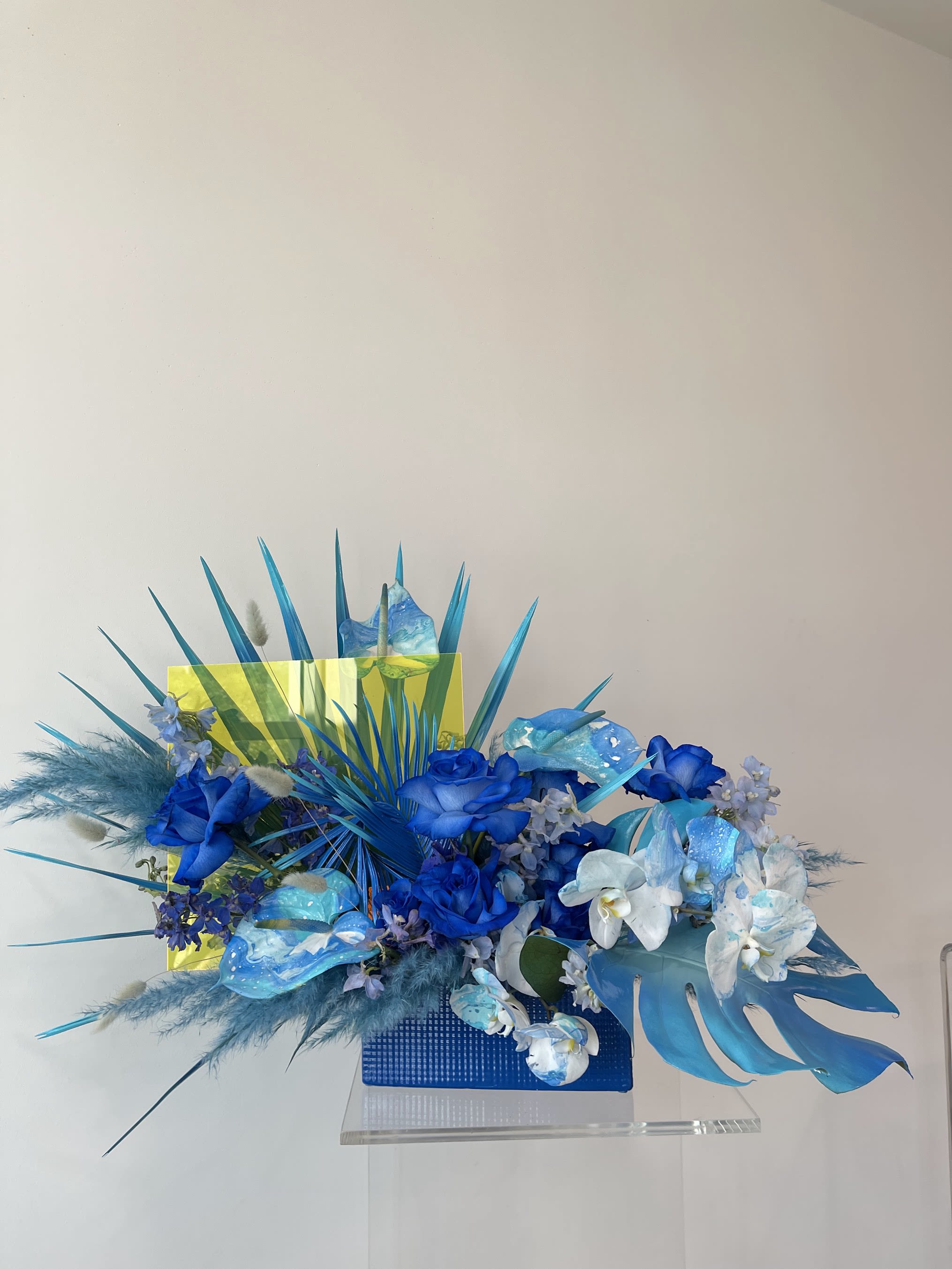 Blue floral arrangement with orchids and roses in a rectangular vase