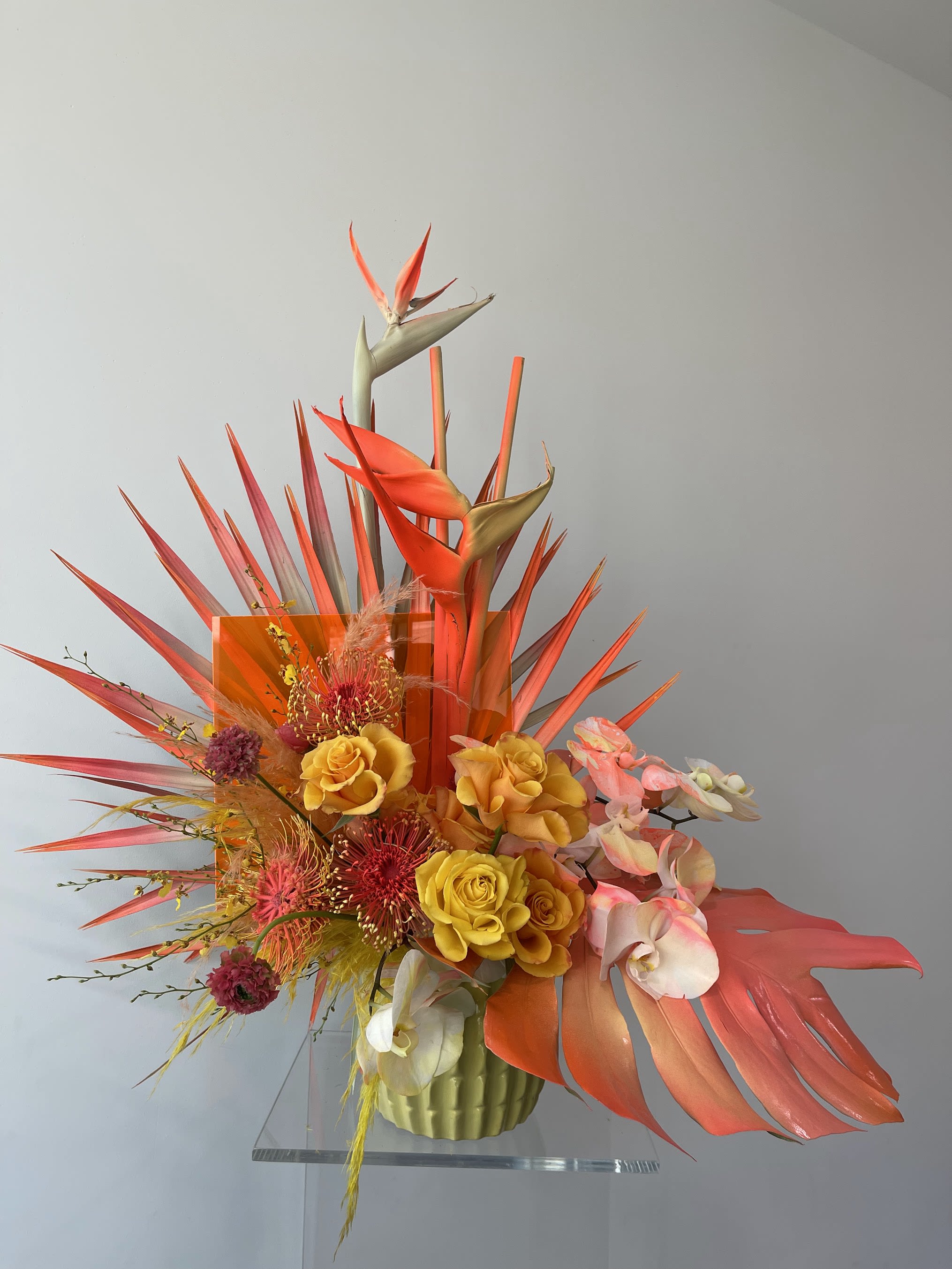 Tropical floral arrangement with orange birds of paradise and yellow roses in a vase