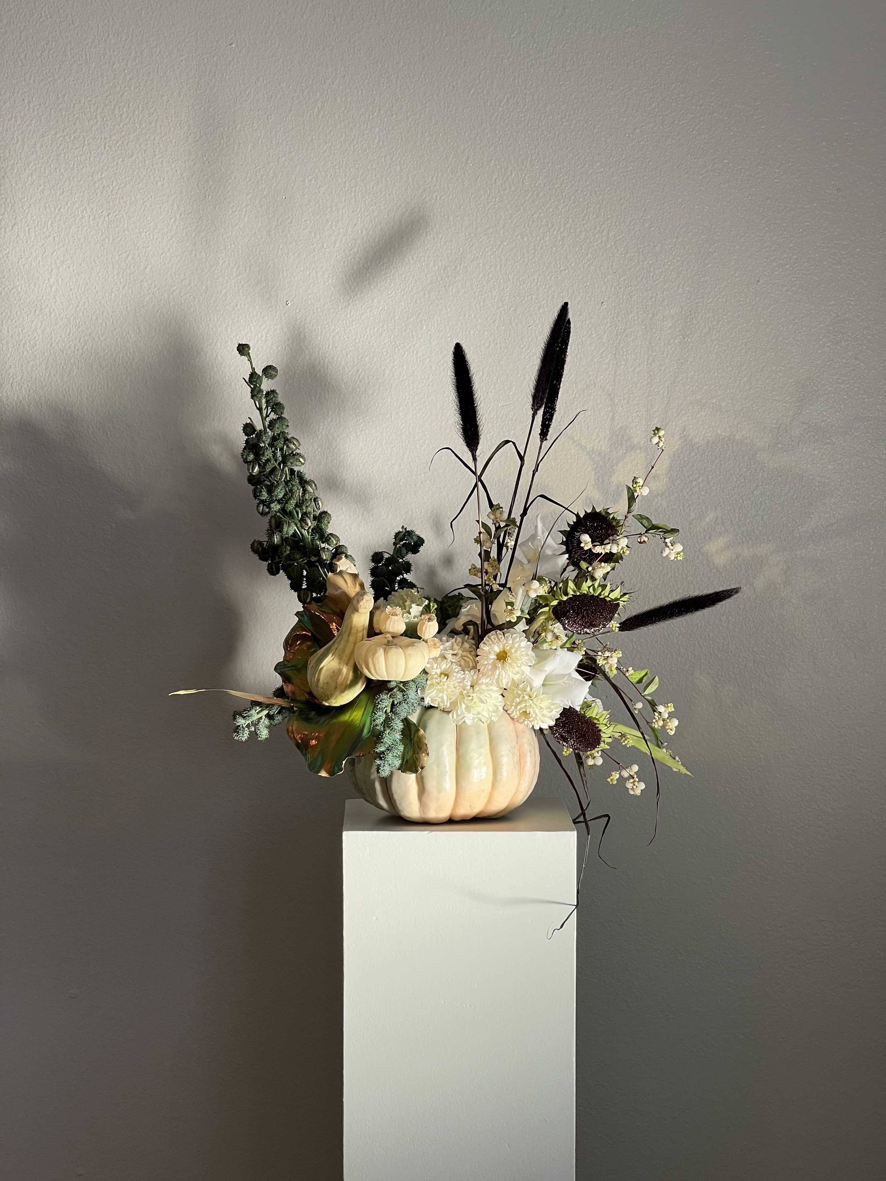 Pumpkin arrangement with white flowers and dark ornamental grasses