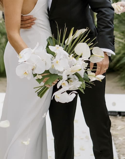 Bride and groom holding a white orchid wedding bouquet