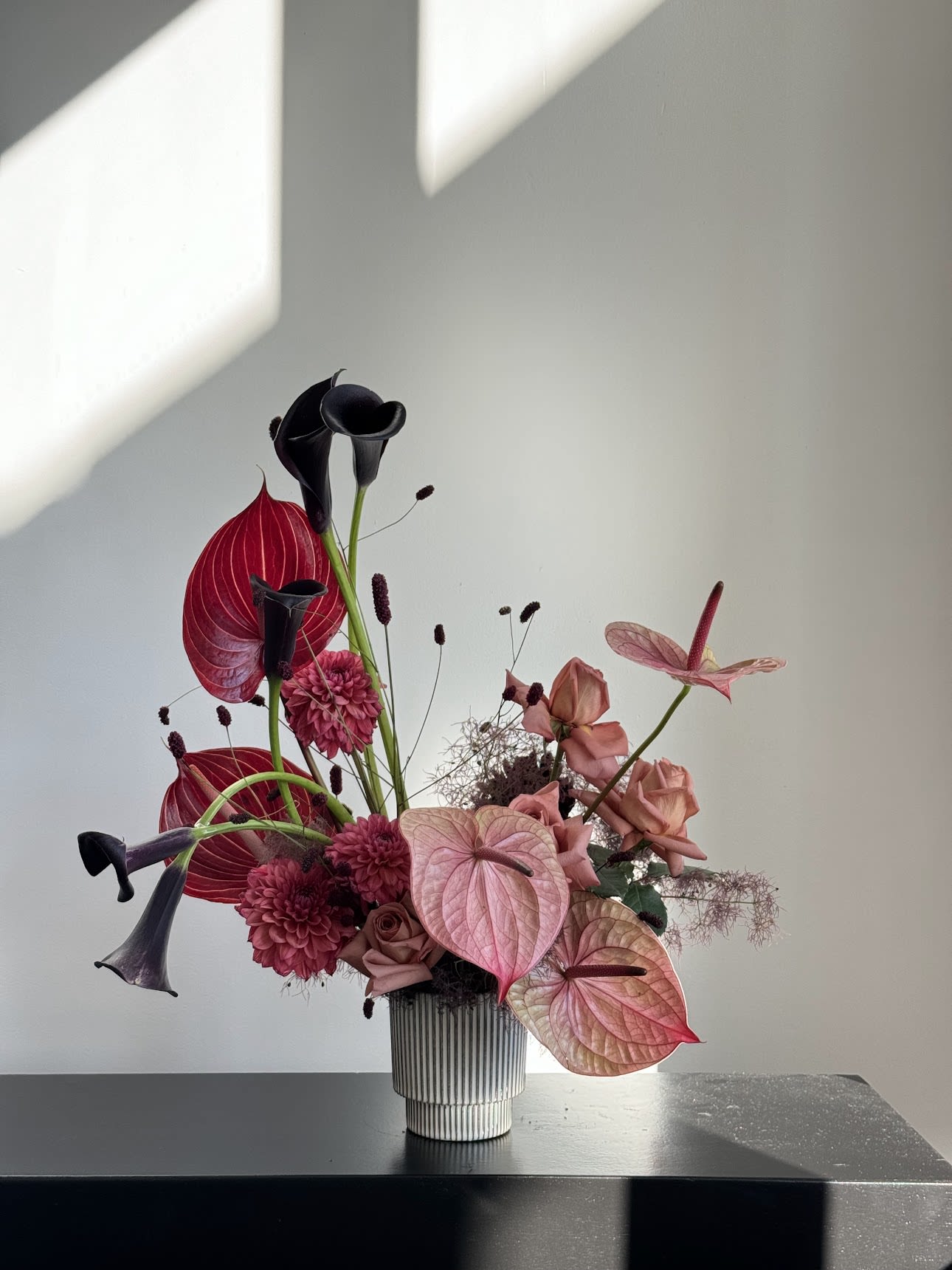 Pink and black floral arrangement in a ribbed vase
