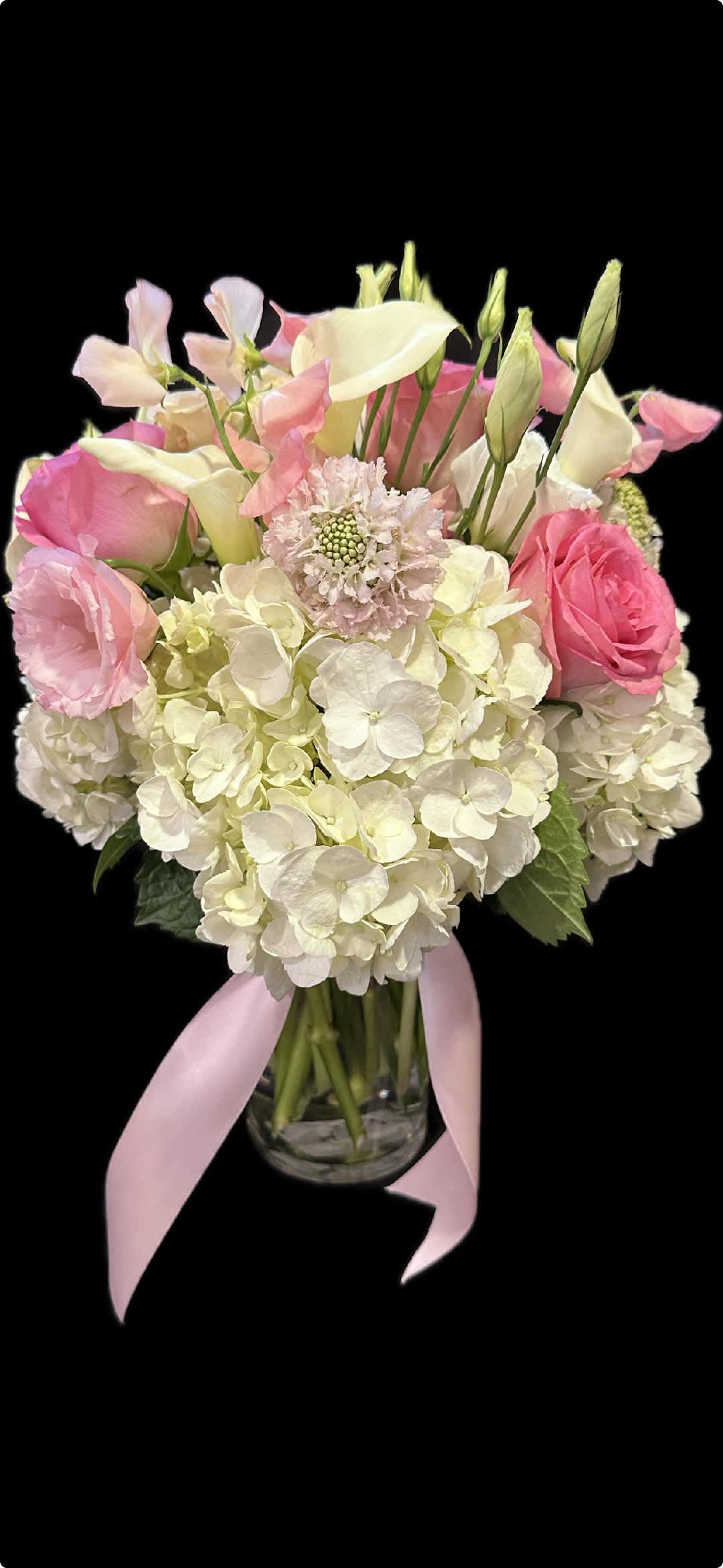 Pink and white bouquet in a glass vase with a pink ribbon