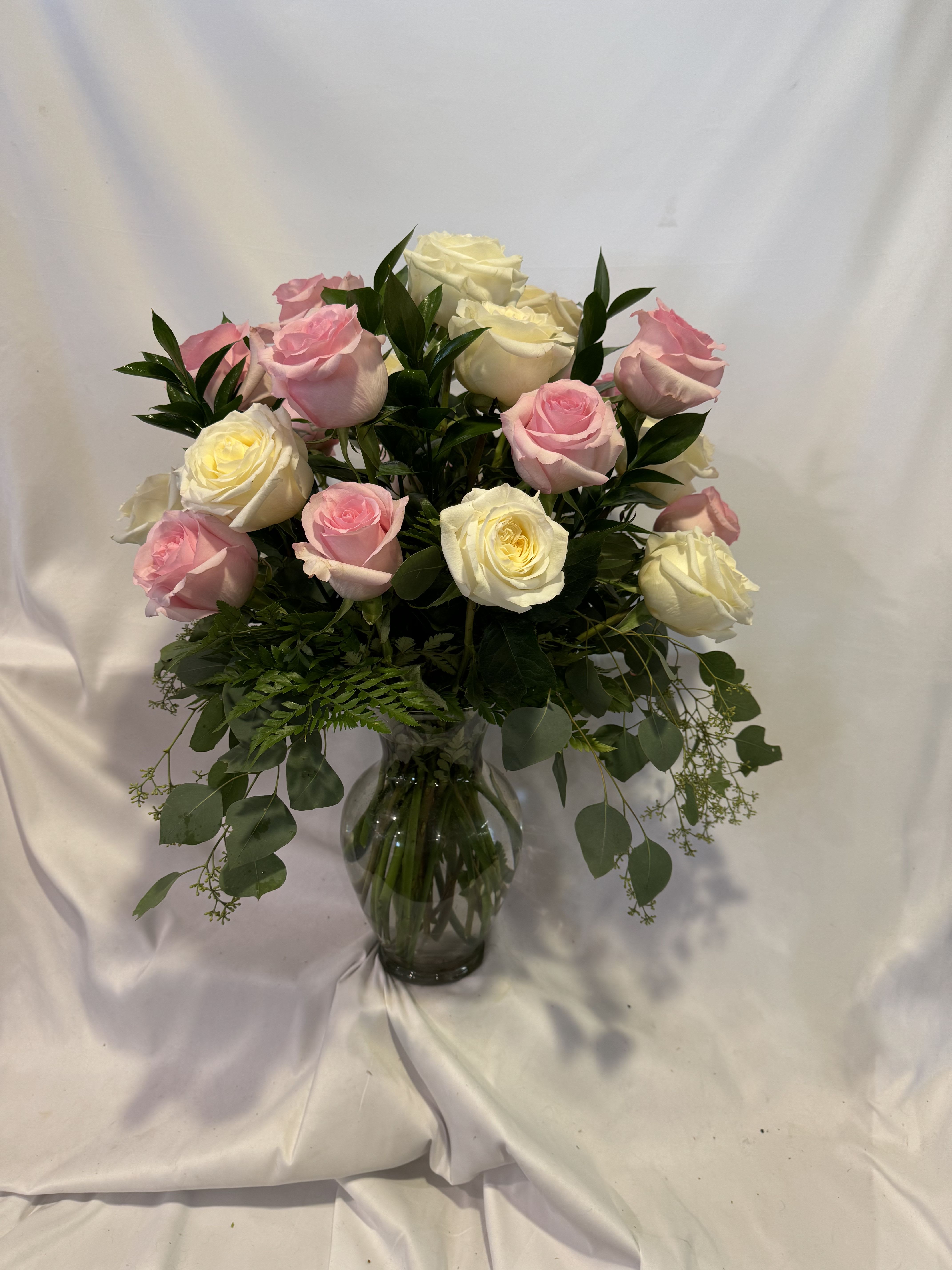Pink and white roses arranged in a glass vase