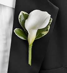 White calla lily boutonniere with green leaves on a black jacket
