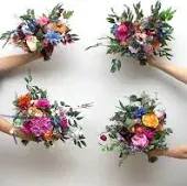 Four small mixed flower bouquets held in hands against a white background