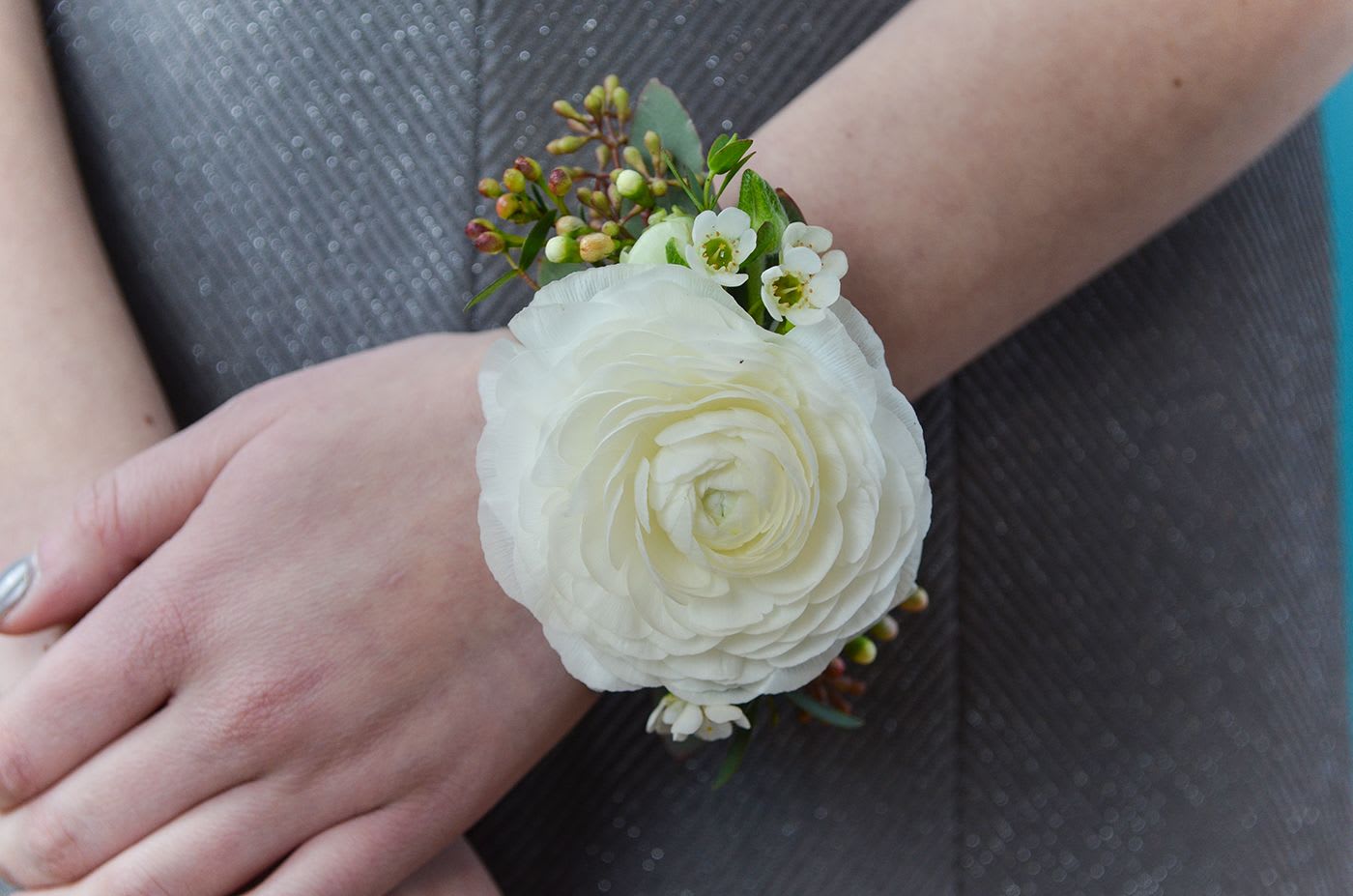 White flower wrist corsage with small green accents
