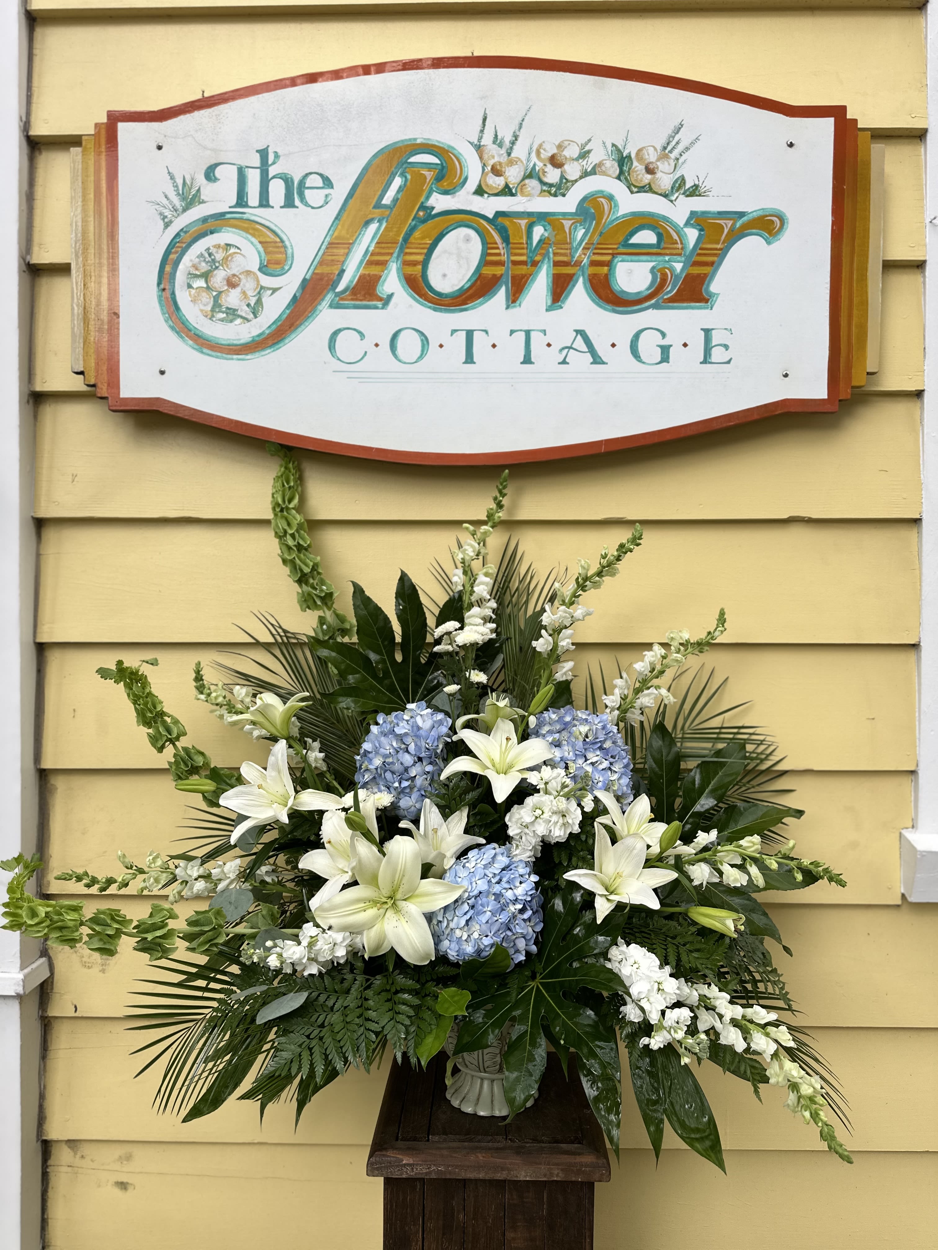 Large floral arrangement with white lilies and blue hydrangeas in a vase