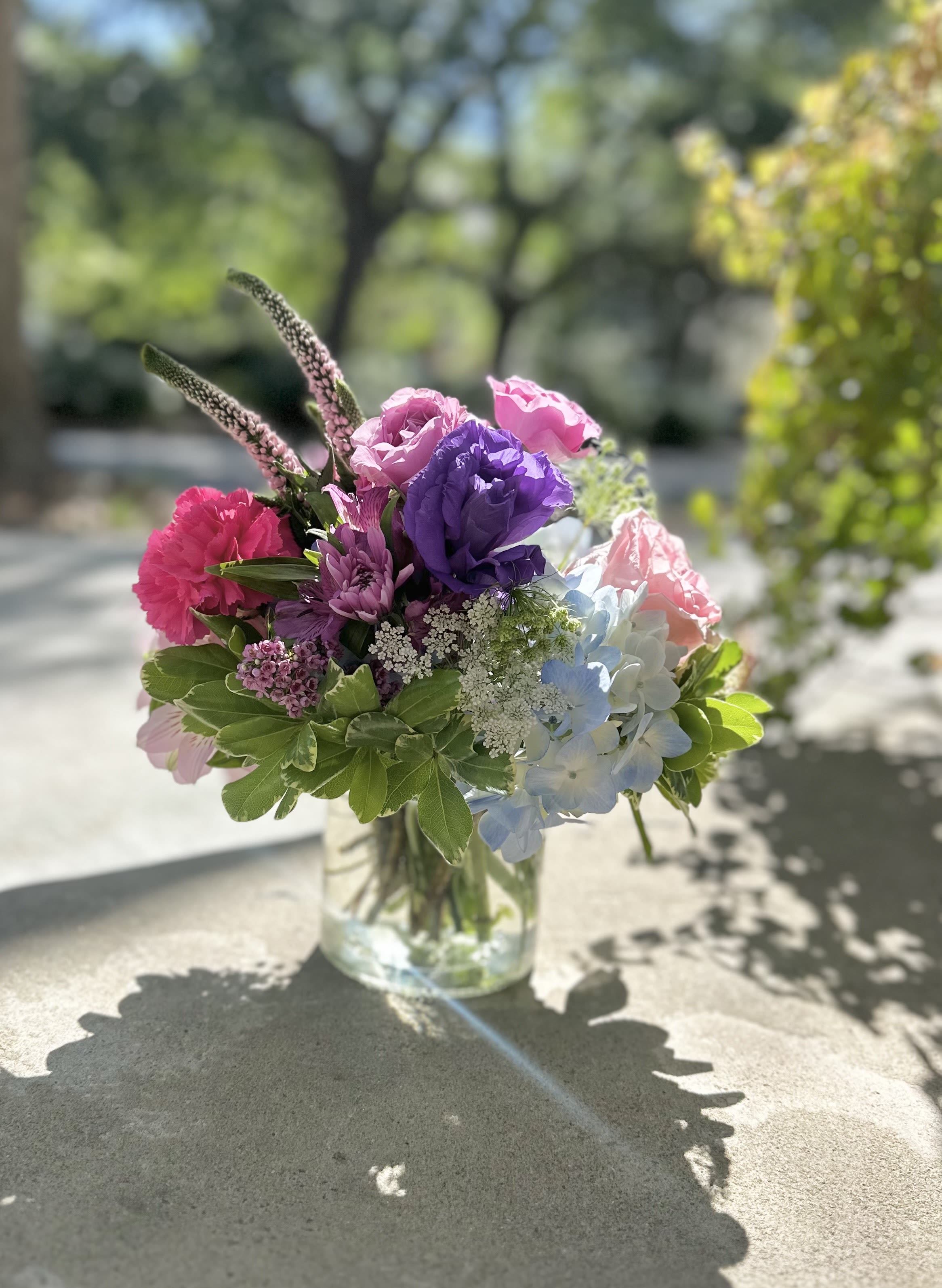 Colorful bouquet in a clear glass vase with pink, purple, and blue blooms
