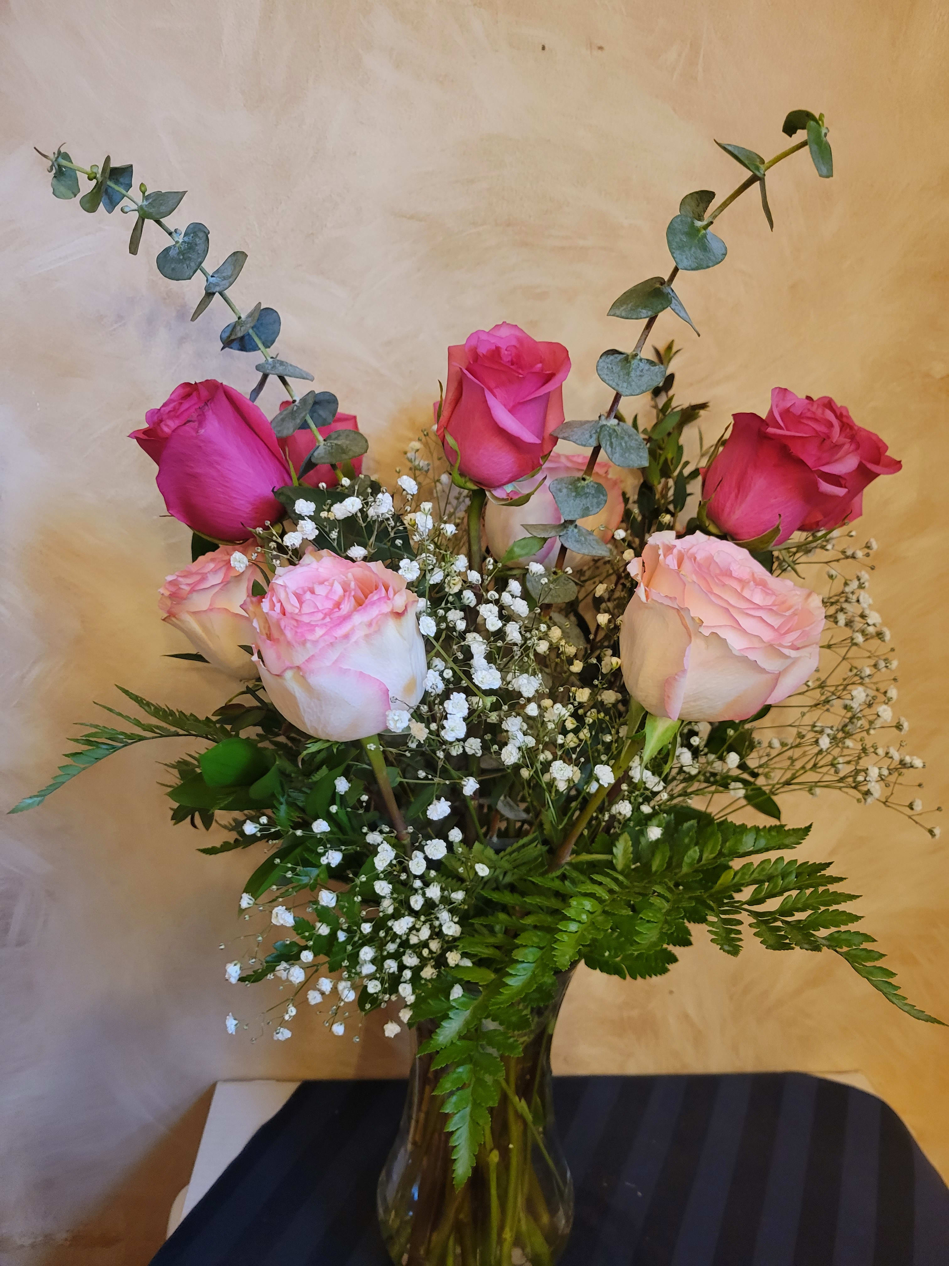 Pink roses in a glass vase with baby's breath and eucalyptus