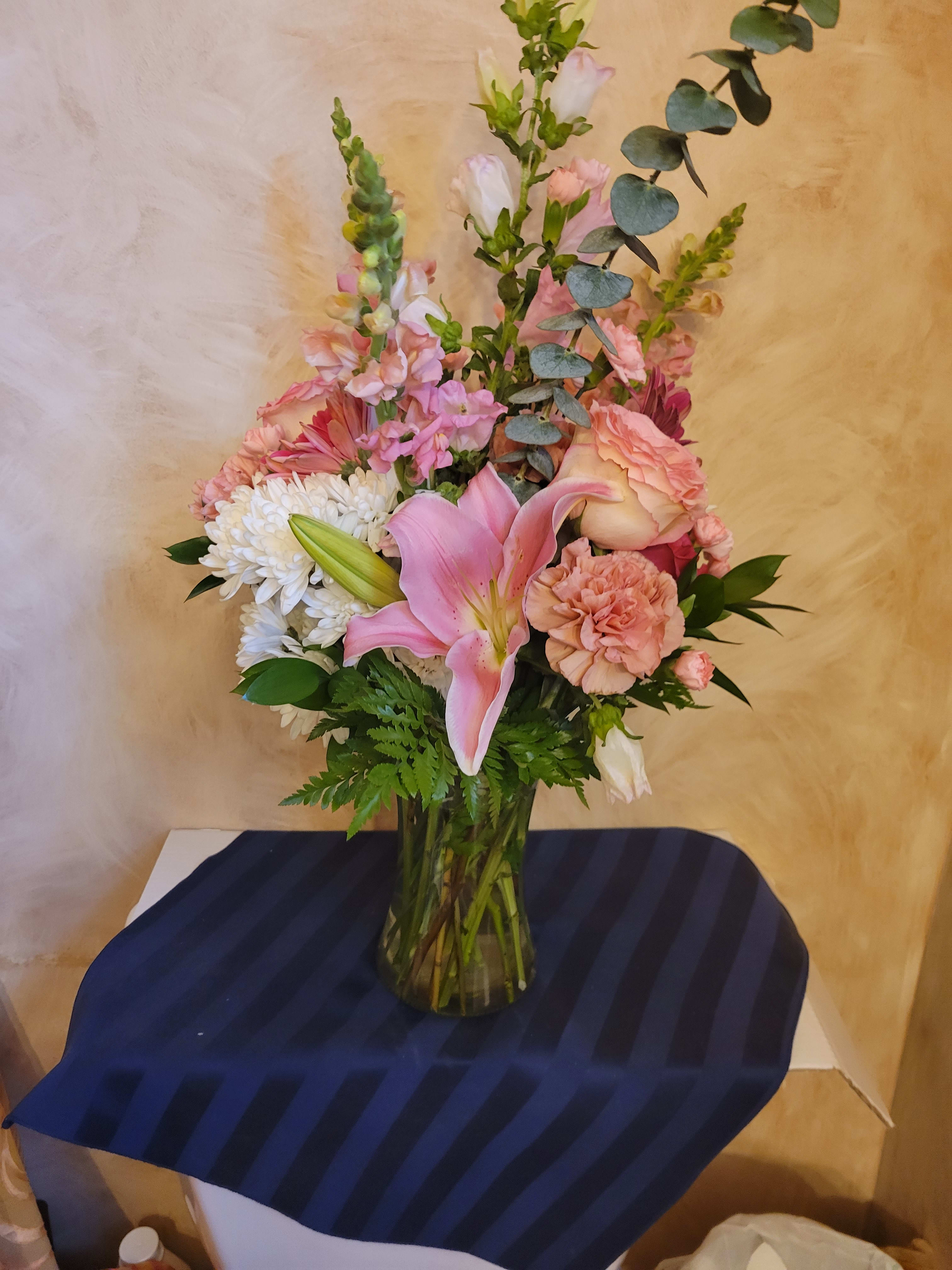 Pink lily and mixed pastel flowers in a glass vase