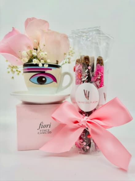 Pink petals in a decorative cup beside a wrapped gift with a bow