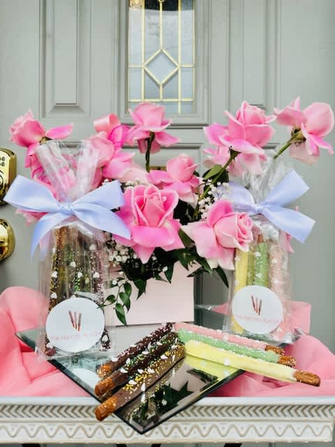Pink roses in gift bags with chocolate-covered pretzel rods on a tray