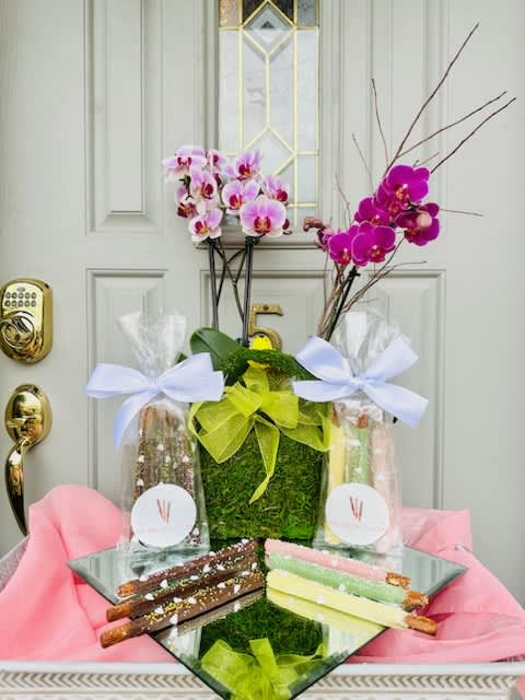 Orchid arrangement with gift bags and chocolate-covered pretzel rods