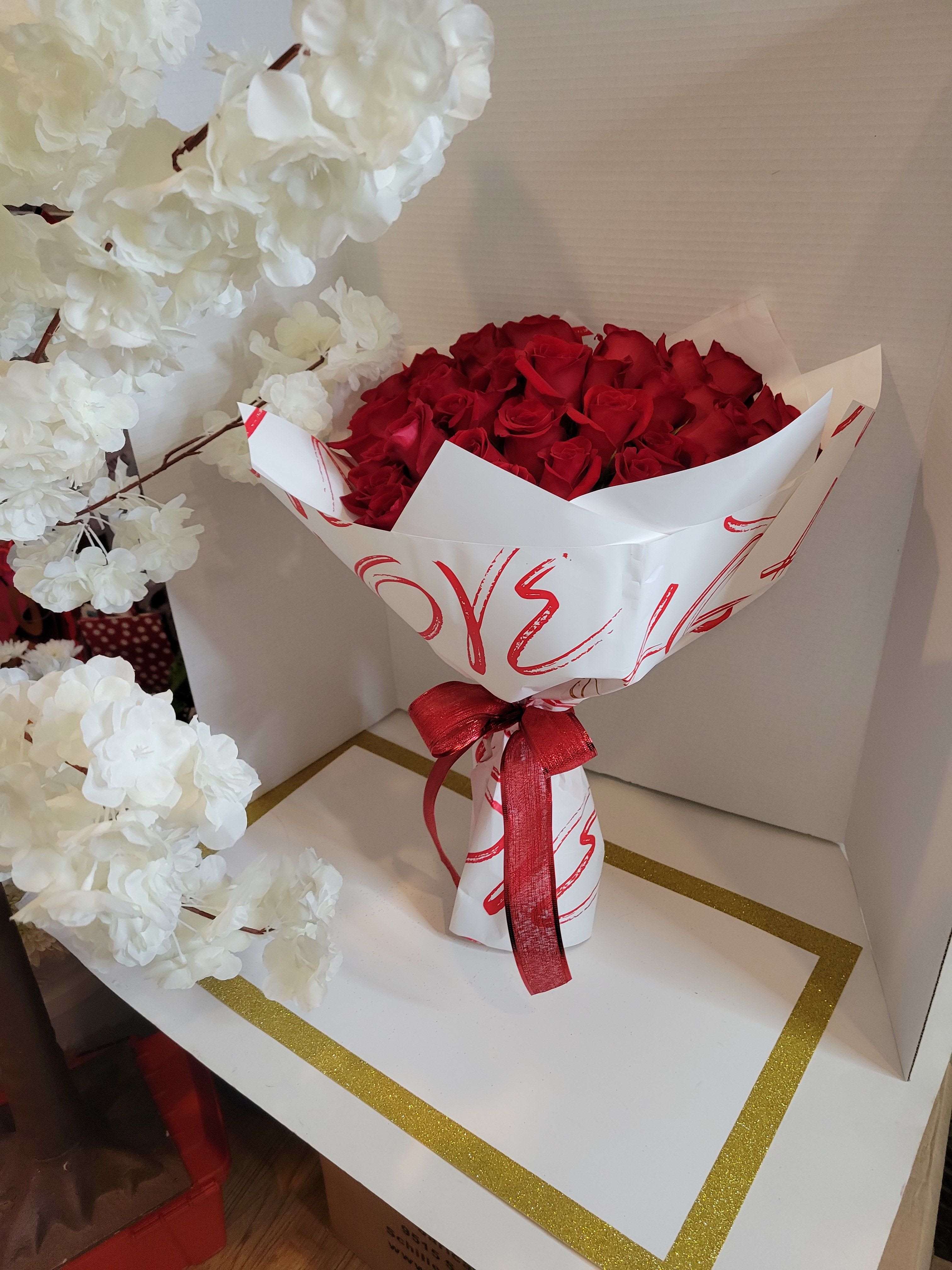 Bouquet of red roses wrapped in white paper with a red ribbon