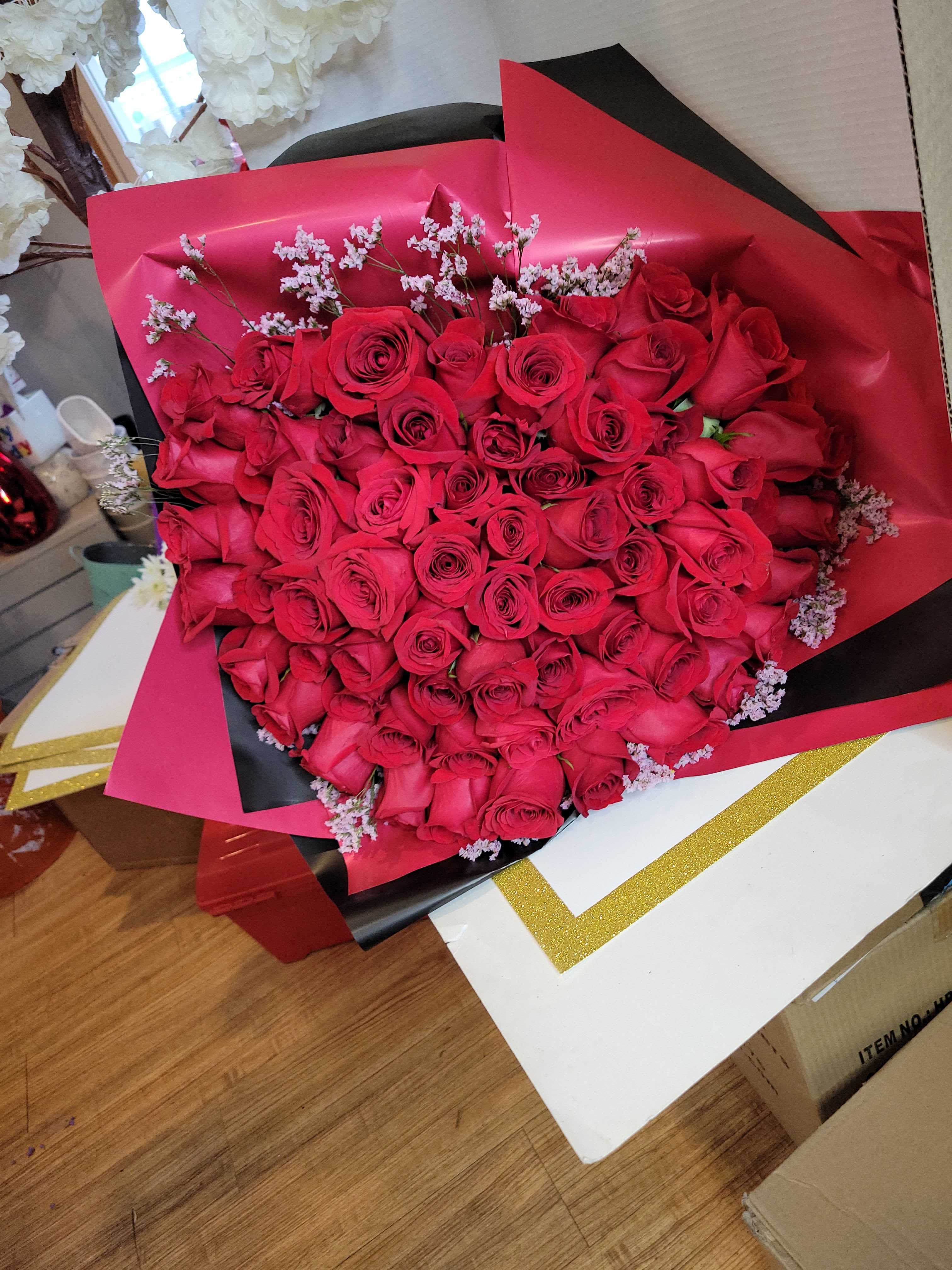 Large bouquet of red roses wrapped in pink and black paper