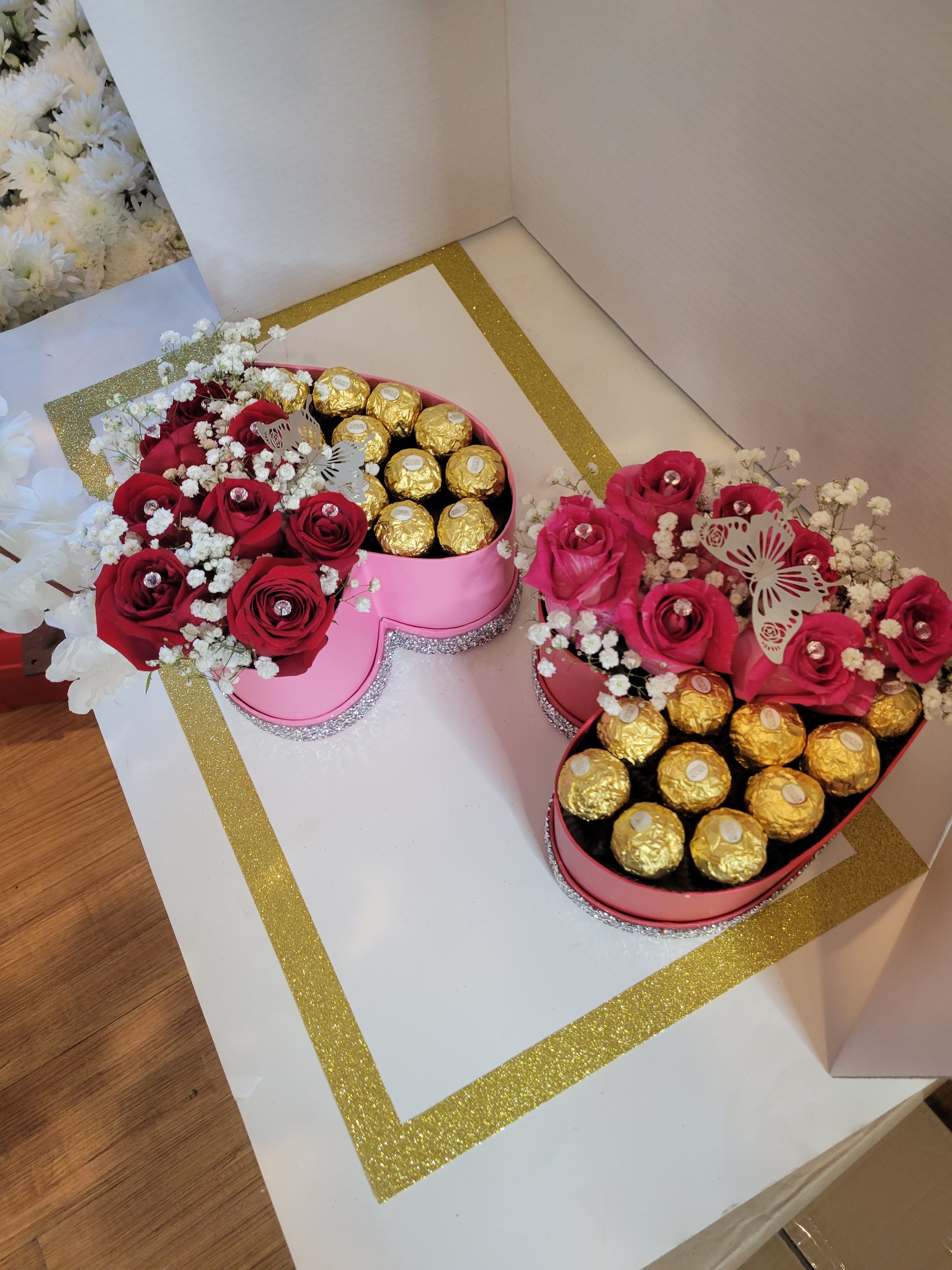 Heart-shaped boxes with red roses and gold-wrapped chocolates