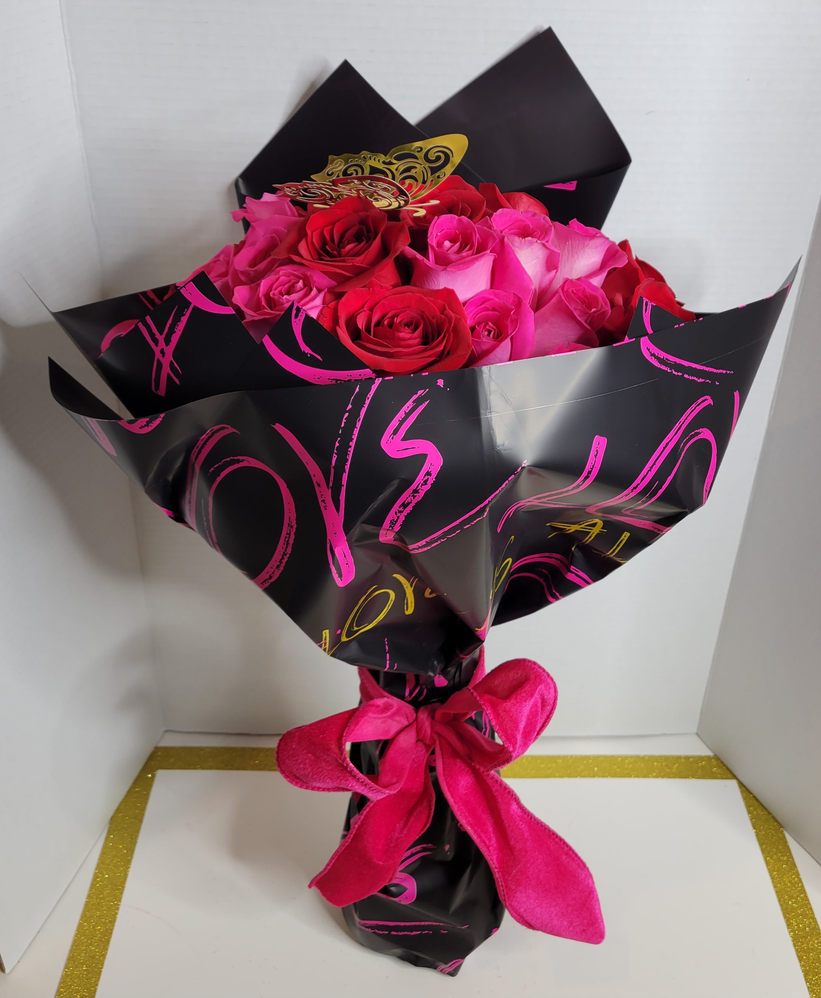 Bouquet of pink and red roses wrapped in black paper with a pink ribbon