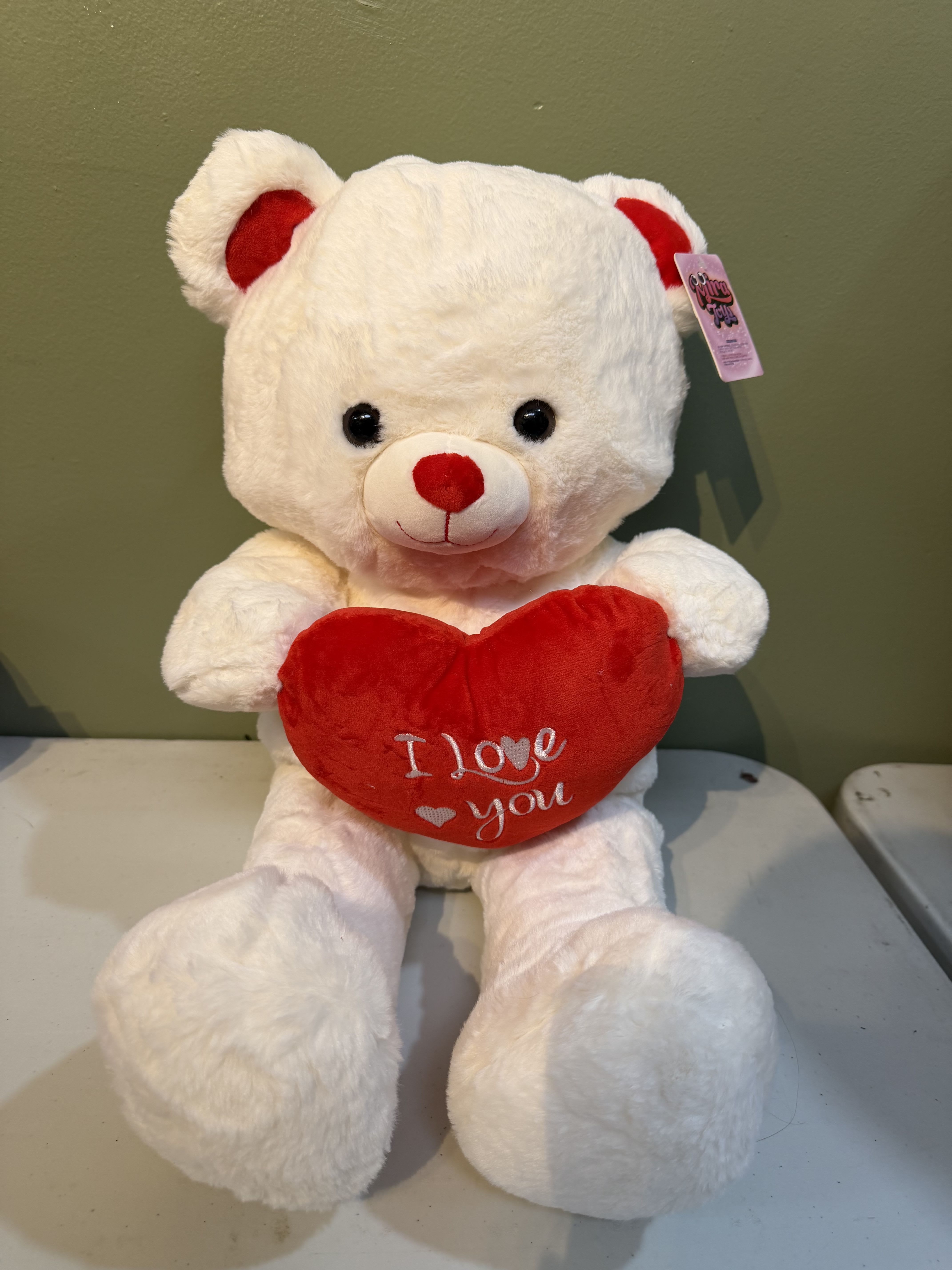 White teddy bear holding a red heart with "I love you" text