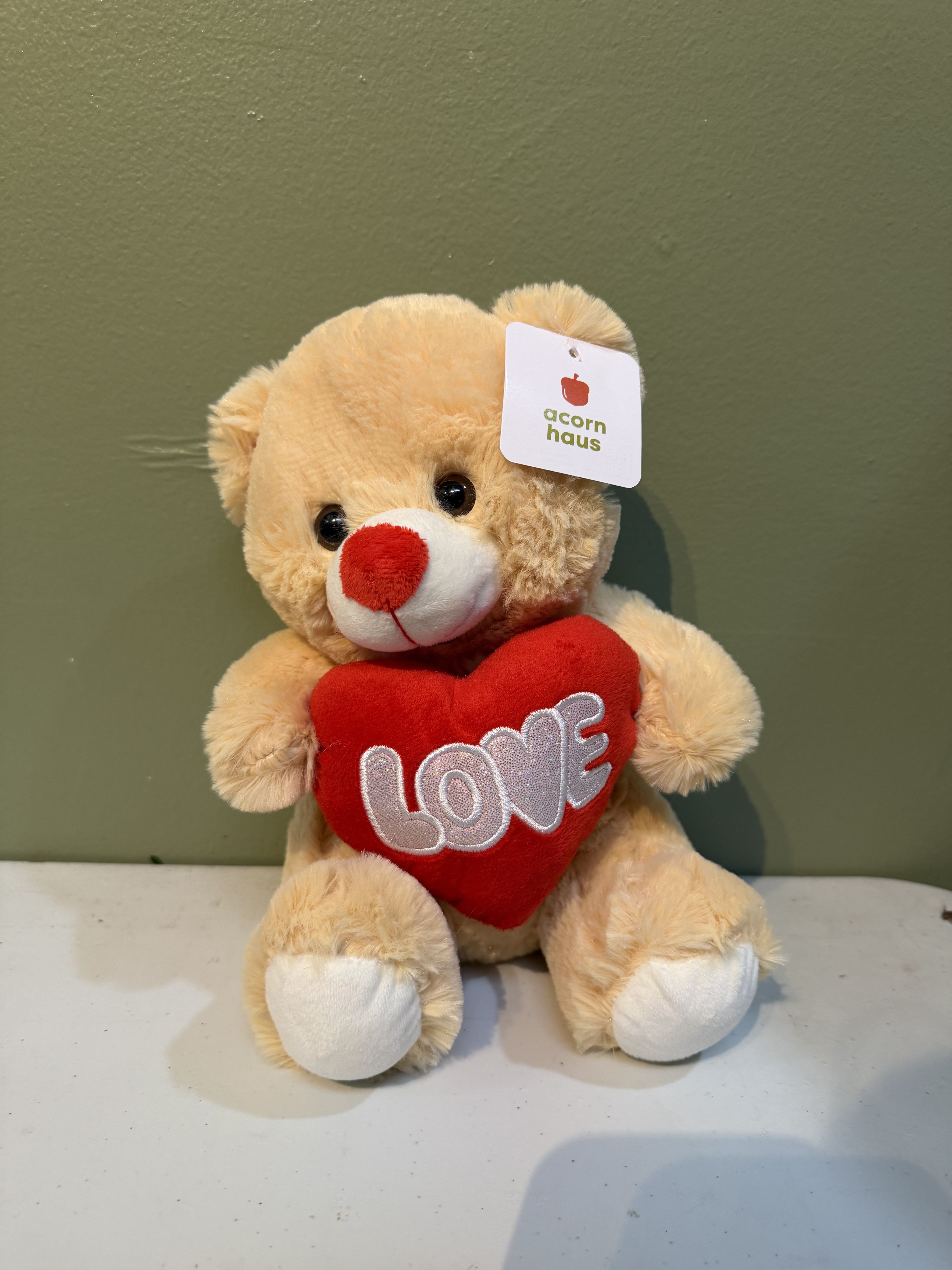 Plush teddy bear holding a red heart with the word LOVE