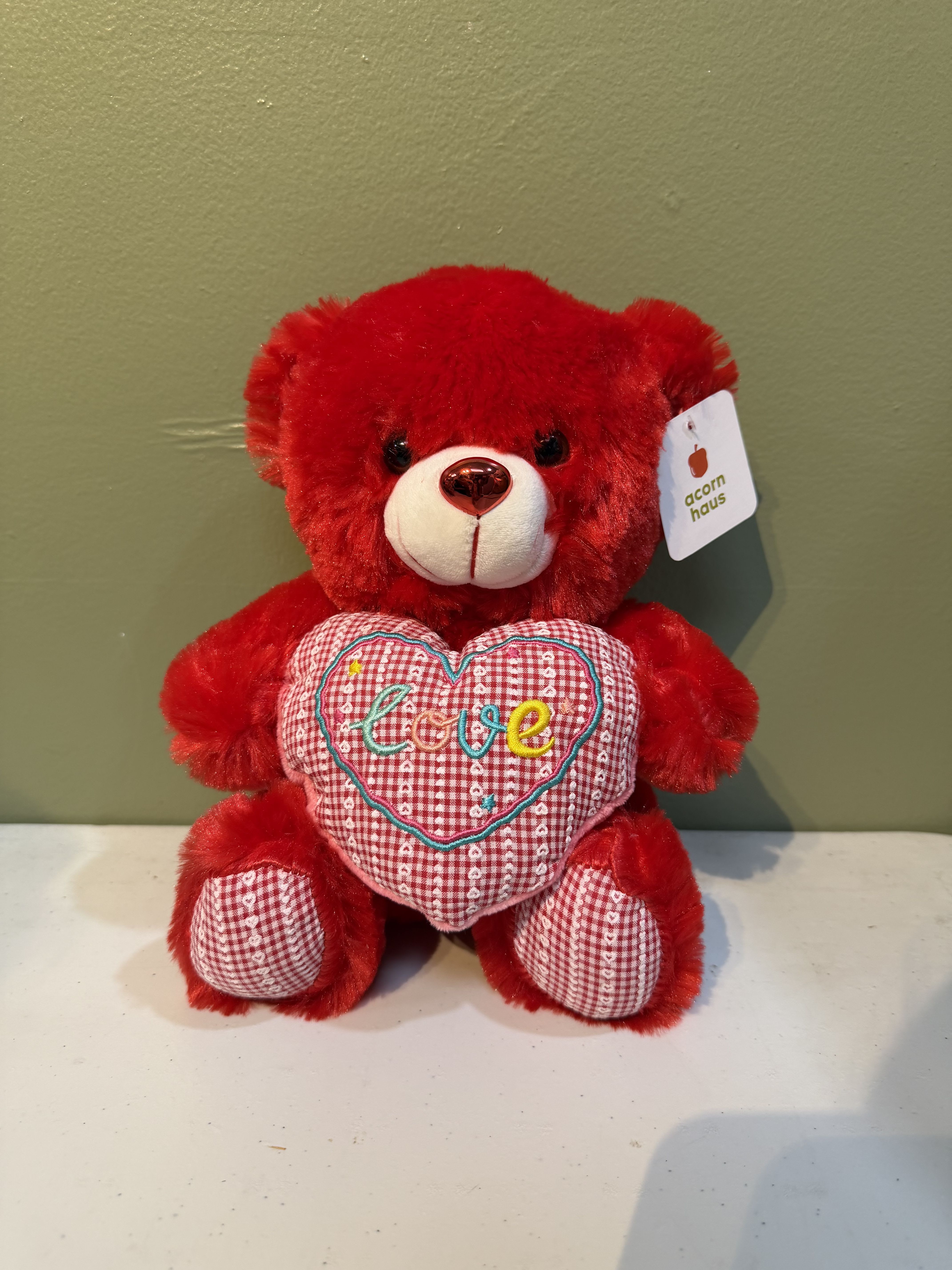 Red teddy bear holding a heart with the word love