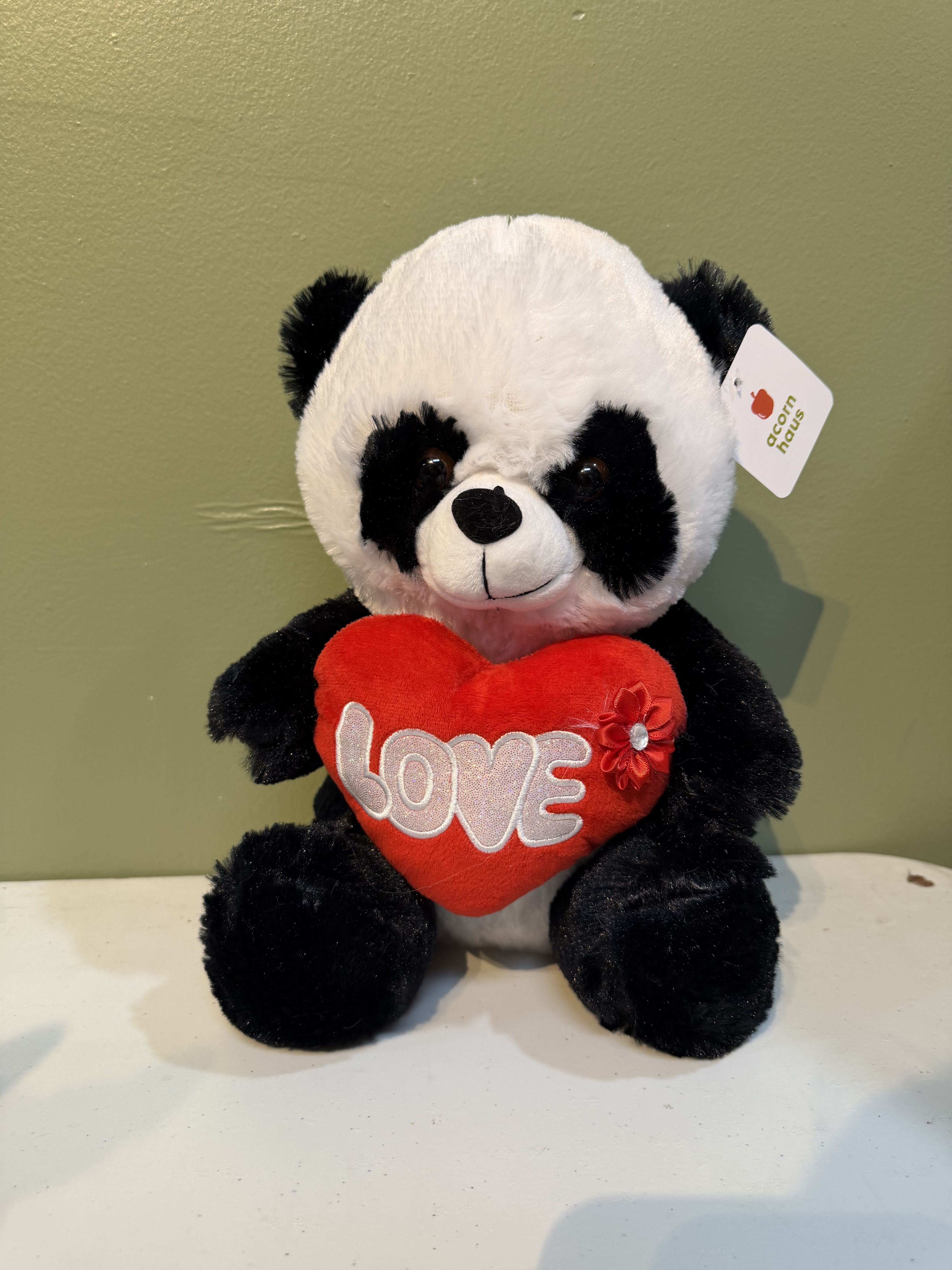 Plush panda holding a red heart with the word LOVE