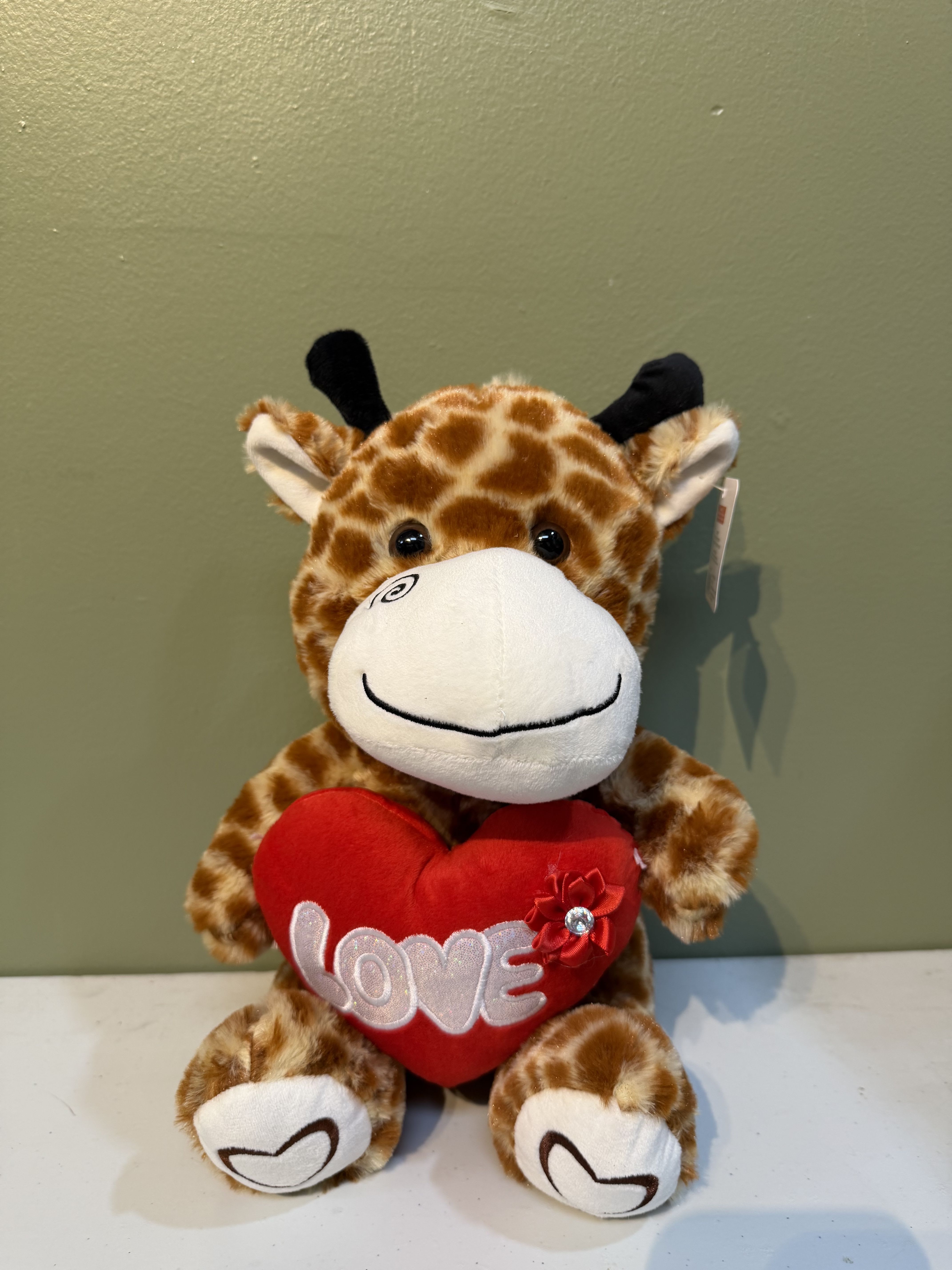 Plush giraffe holding a red heart with the word LOVE