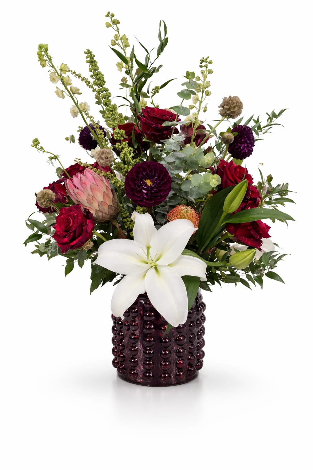 Mixed bouquet with red roses, white lily, and purple blooms in a dark vase