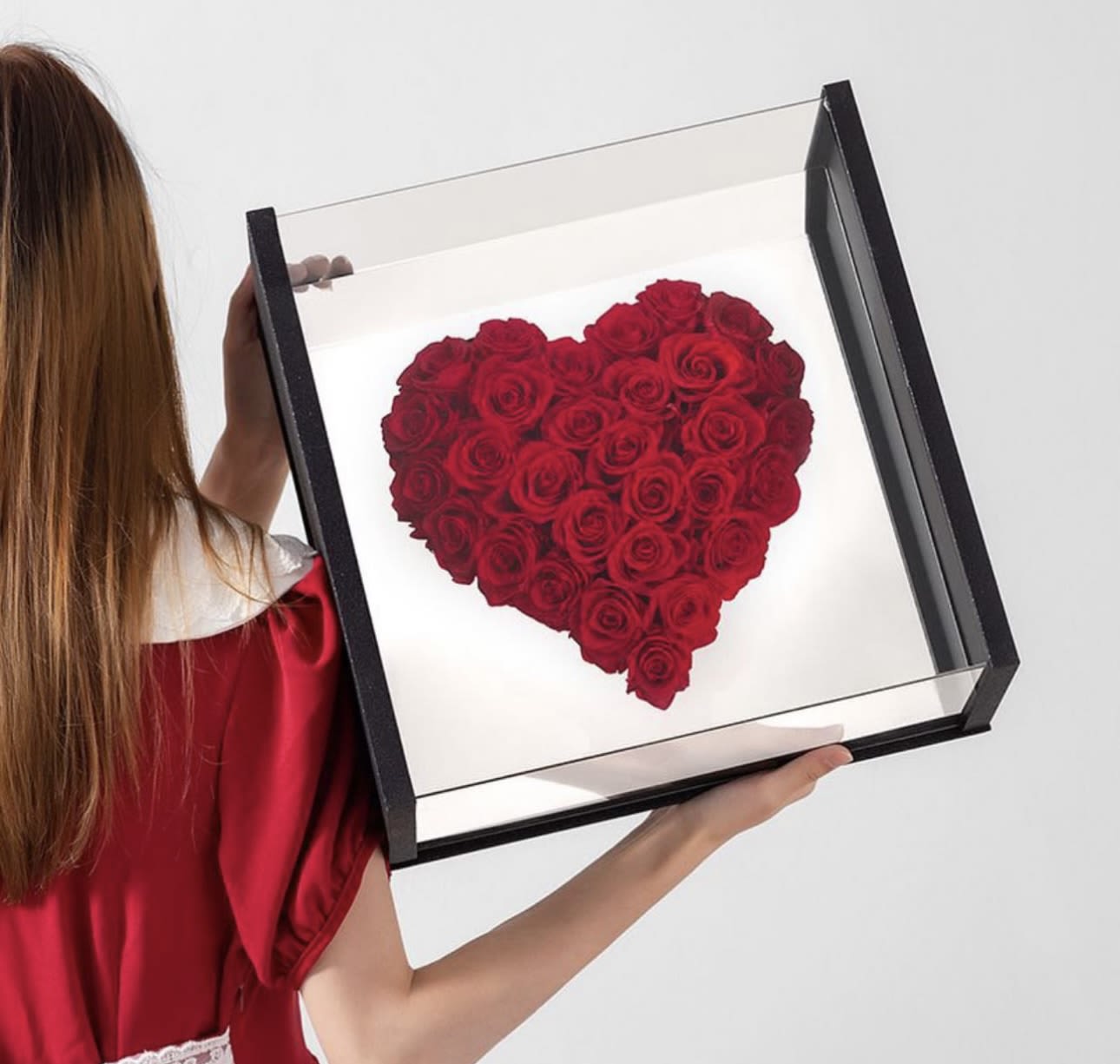 Heart-shaped arrangement of red roses in a black display box