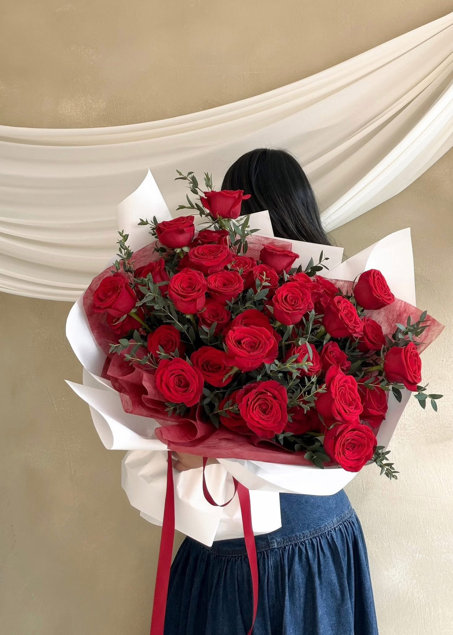 Large bouquet of red roses wrapped in white and red paper