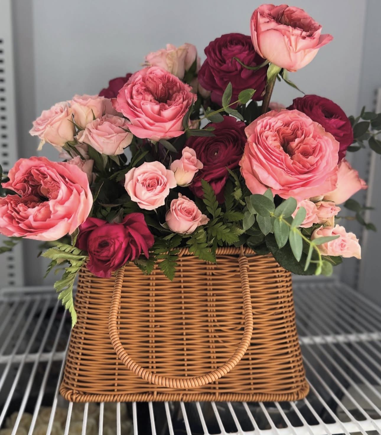 Pink and burgundy roses arranged in a wicker basket