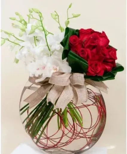 ORCHID &amp; ROSE AFFAIR - A gorgeous, artistically arranged bouquet of dendrobium and cymbidium orchids cozied up next to romantic red roses in a pillow-shaped vase. This arrangement is sure to win the hearts of your beloved.