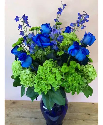 Blue roses and green hydrangeas in a dark glass vase