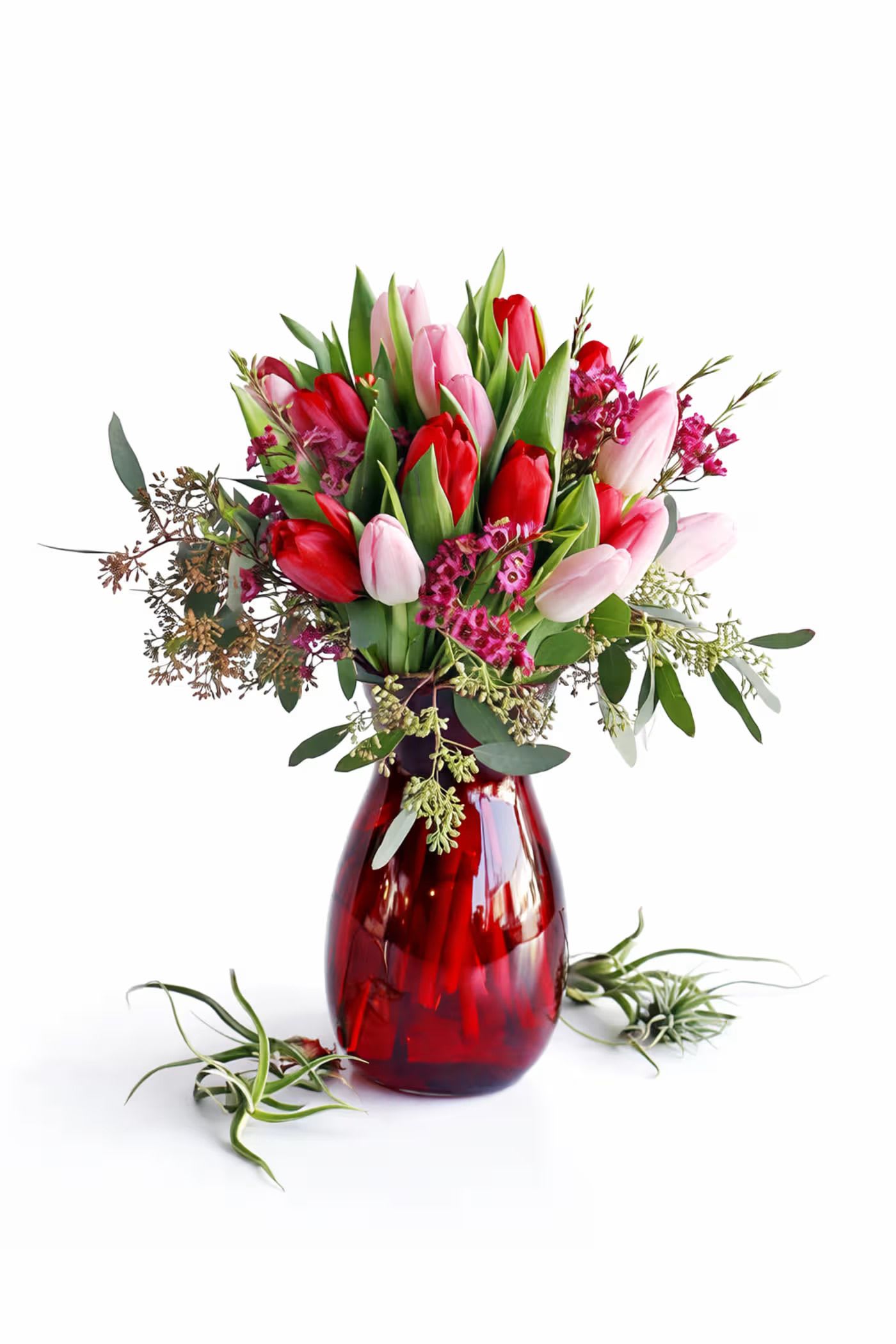 Pink and red tulips arranged in a red glass vase