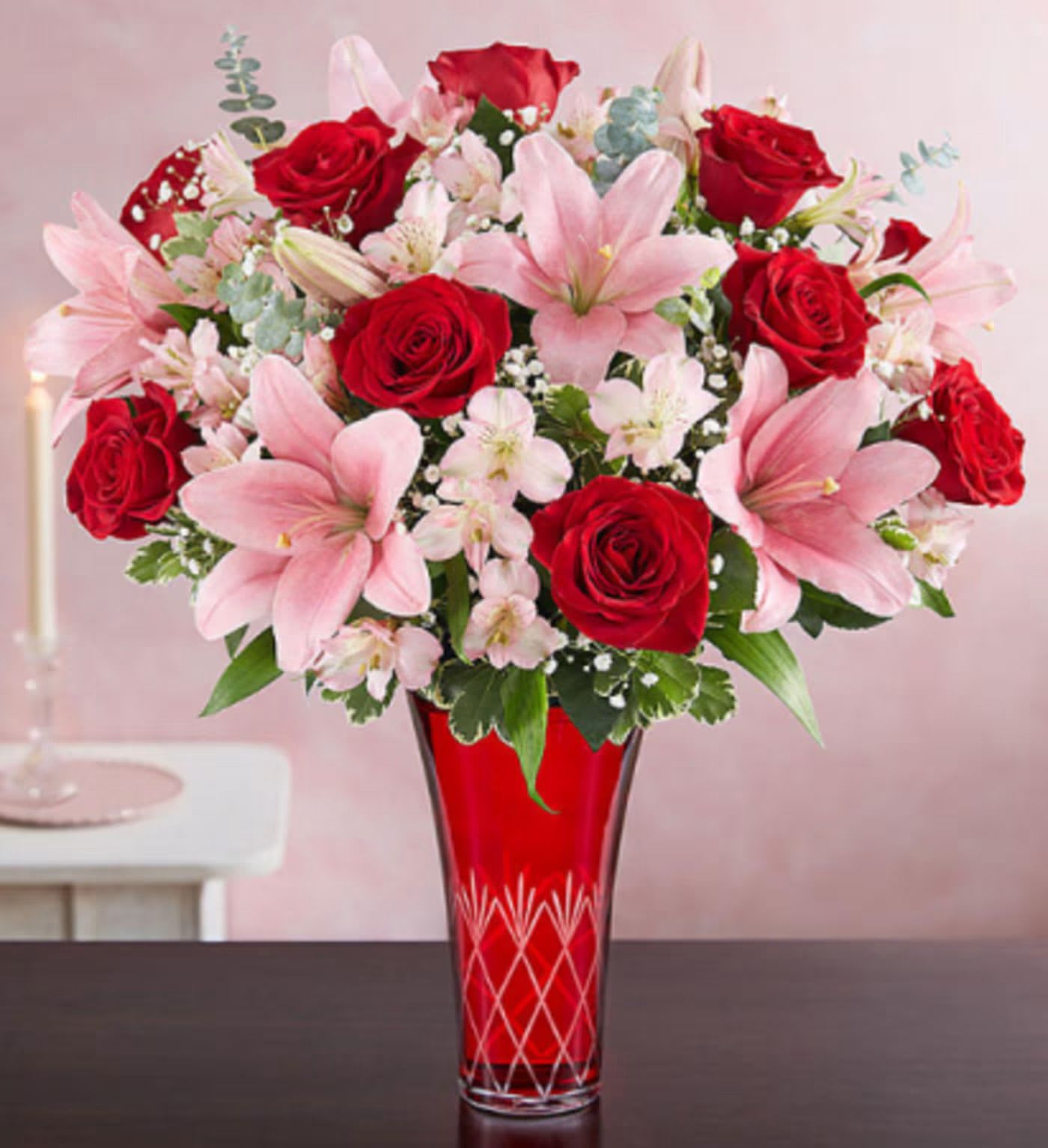 Tall bouquet of red roses and pink lilies in a red etched glass vase