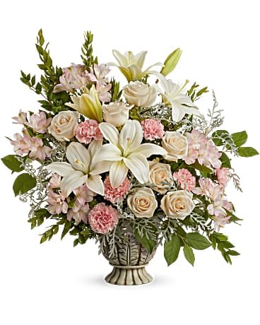 Teleflora's Peaceful Joy Bouquet - A peaceful yet powerful showing of support and love, this dramatic rose bouquet is presented in a classic urn. This bouquet features crÃ¨me roses, white asiatic lilies, light pink alstroemeria, pink carnations, silver lace dusty miller, lemon leaf and myrtle. Delivered in a Thoughtful Tribute Pot.