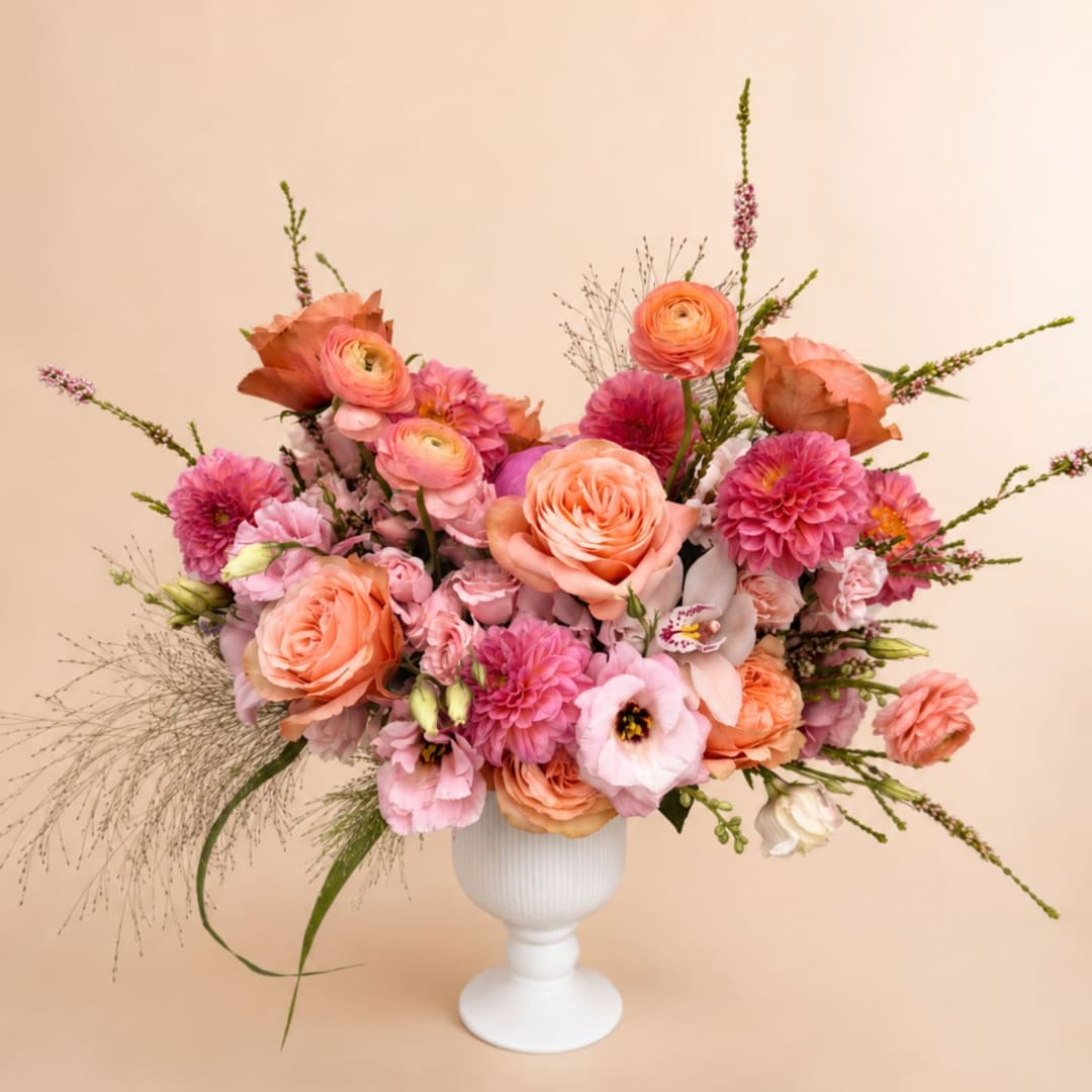 Peach and pink mixed bouquet in a white pedestal vase