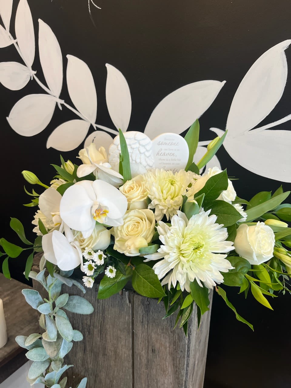 White floral arrangement in a rustic wooden box with orchids and roses